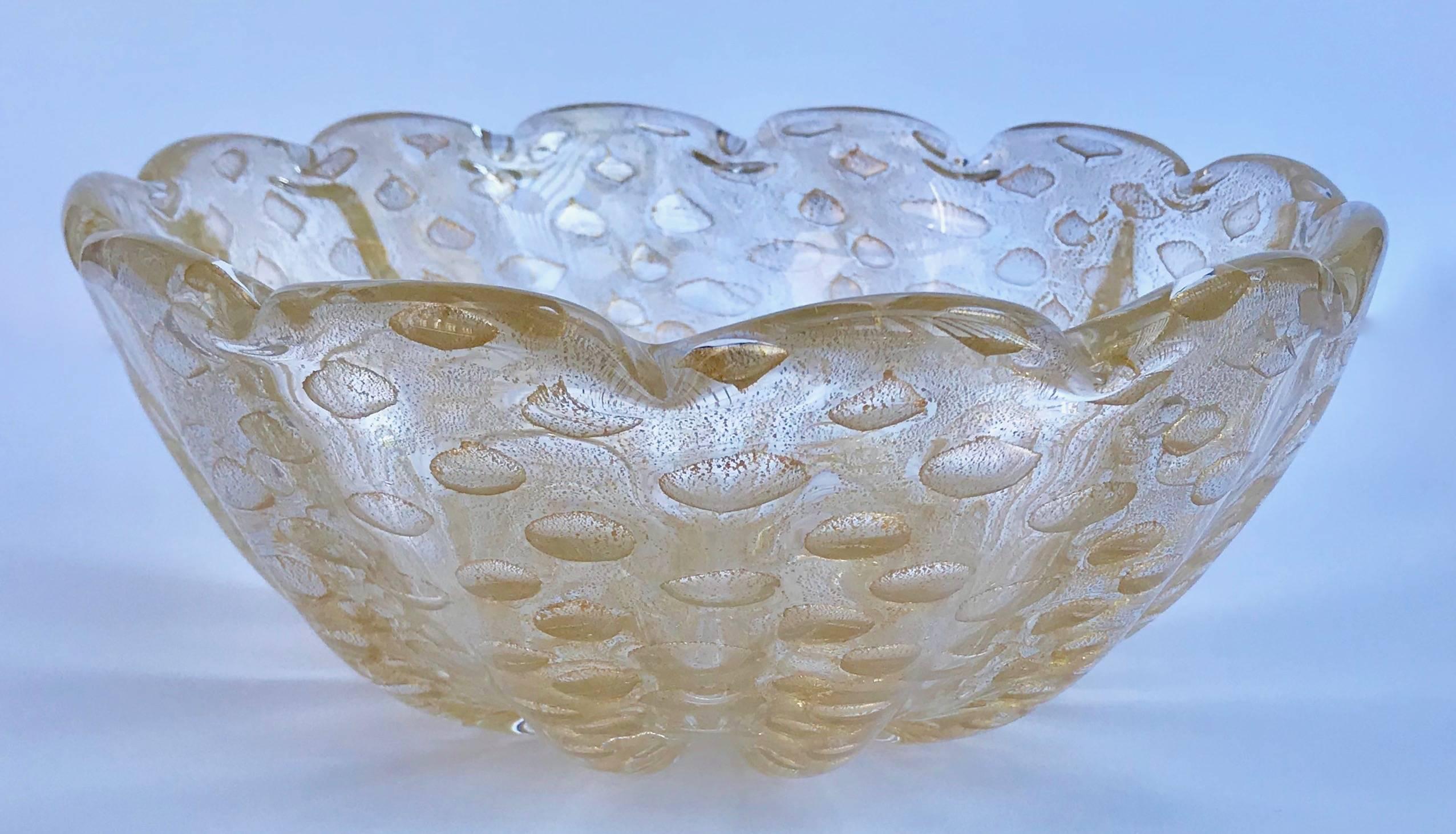 A large and beautifully crafted Italian Murano glass bowl in clear glass with gold inclusions in the bullicante technique attributed to Barovier. Thick glass ribs accentuate beautiful encased in gold control bubbles with a scalloped detail at the