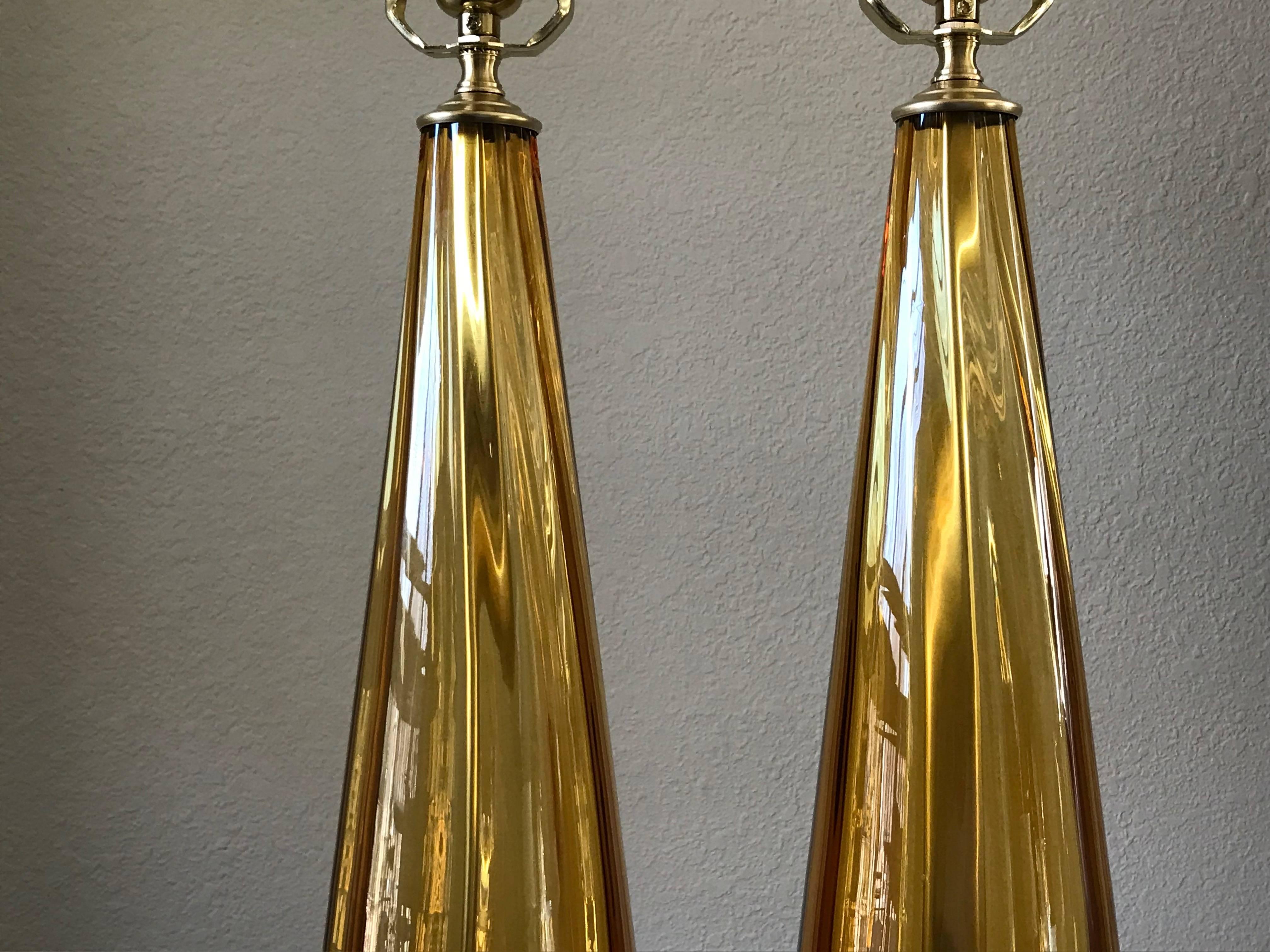 Pair of Italian blown glass lamps in amber colored glass on custom acrylic bases. Newly cleaned and rewired for US with full range dimmer sockets, brass fittings and French style twisted rayon covered cords.

23.25" height to top of sockets X