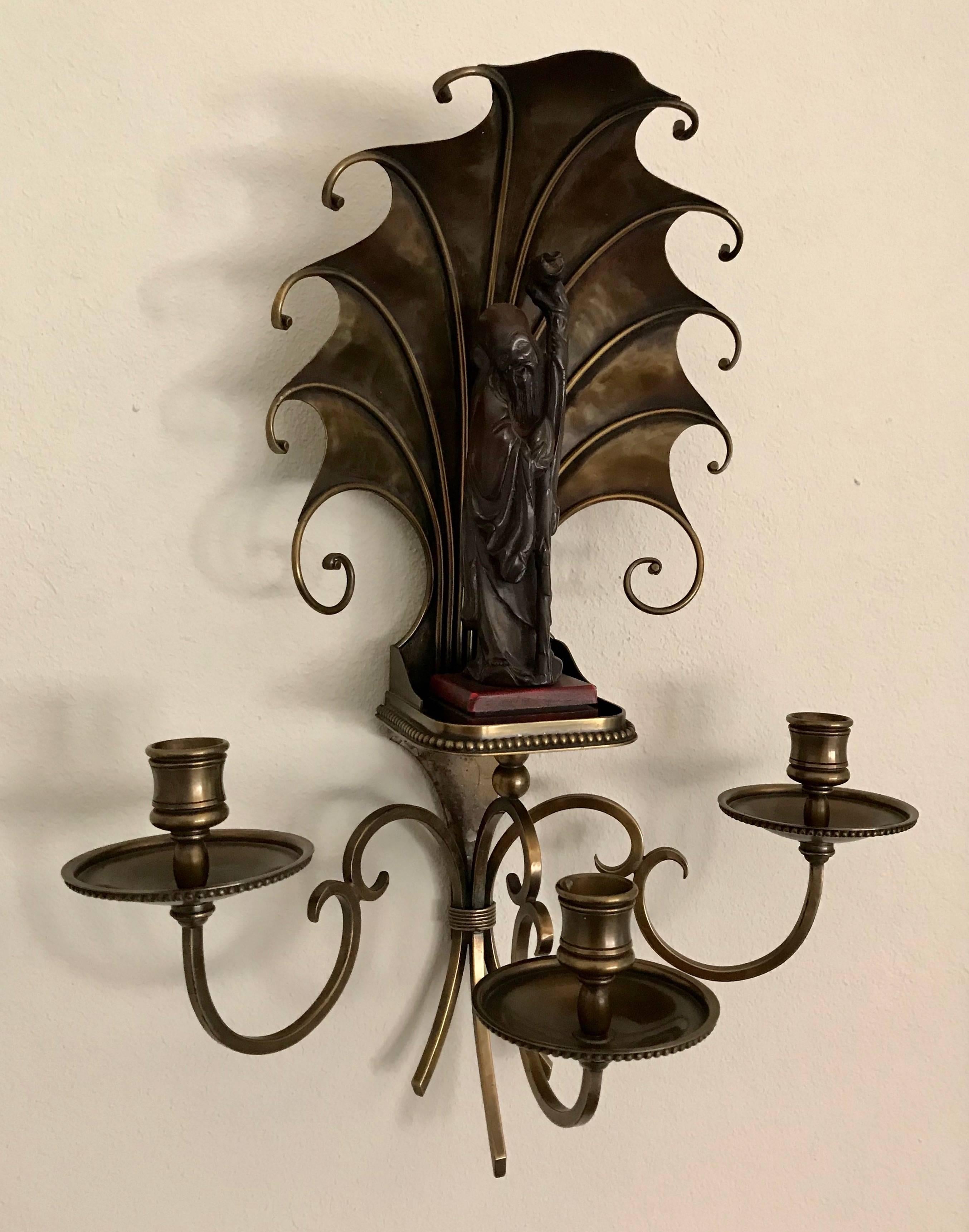 Pair of very unique Art Deco style handcrafted bronze or brass wall sconces featuring Shou Xing, Chinese god of longevity, possibly by Maison Jansen. Scalloped hand-hammered brass shell from back enshrines the figurine. Three delicate scrolled