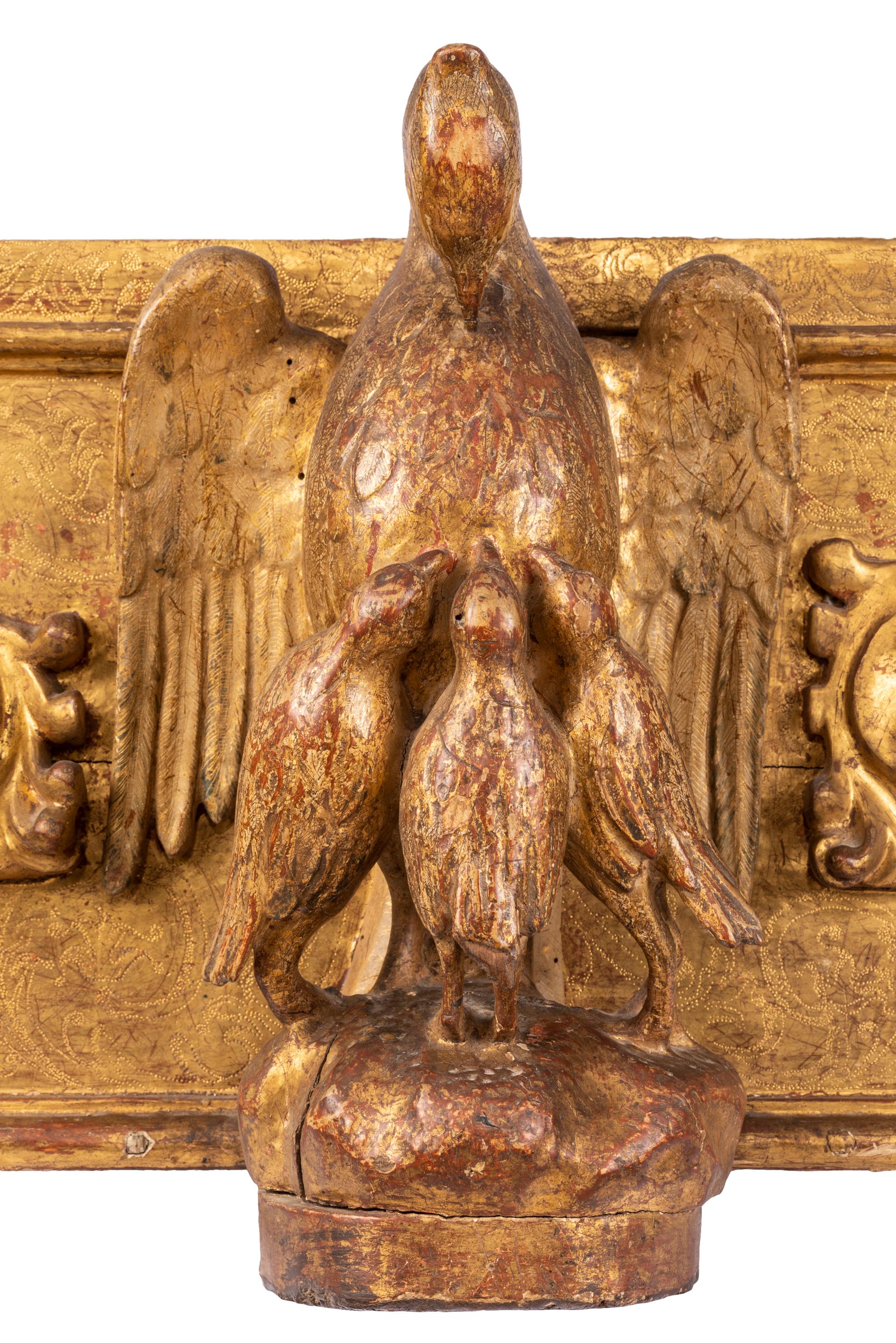 Un pannello scultoreo religioso in legno dorato del XVIII secolo, forse parte di una pala d'altare, il cui motivo decorativo centrale è costituito da un uccello pellicano stilizzato e da pulcini, simbolo della Santa Eucaristia. Abilmente intagliata