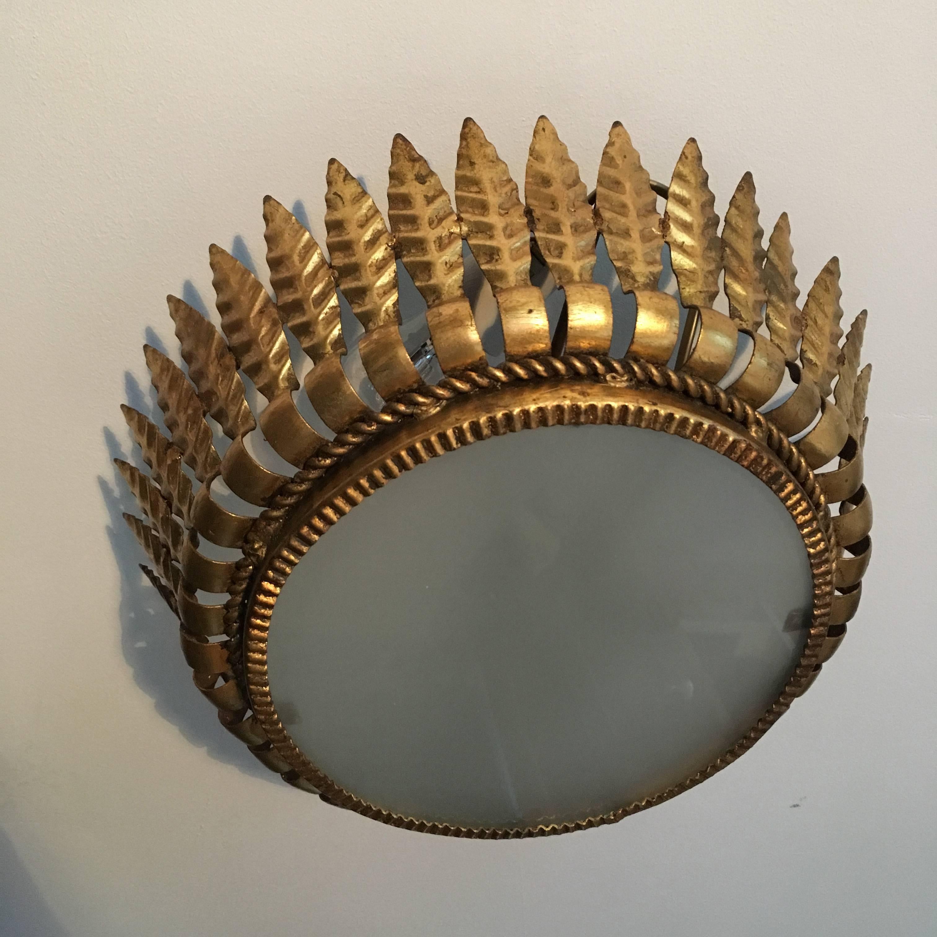 A beautiful gilt metal handcrafted crown ceiling light with twisted border detail and frosted glass diffuser.

The light is a crown of golden textured leaves arranged with a twisted rope effect border surrounding the glass panel. 

This light