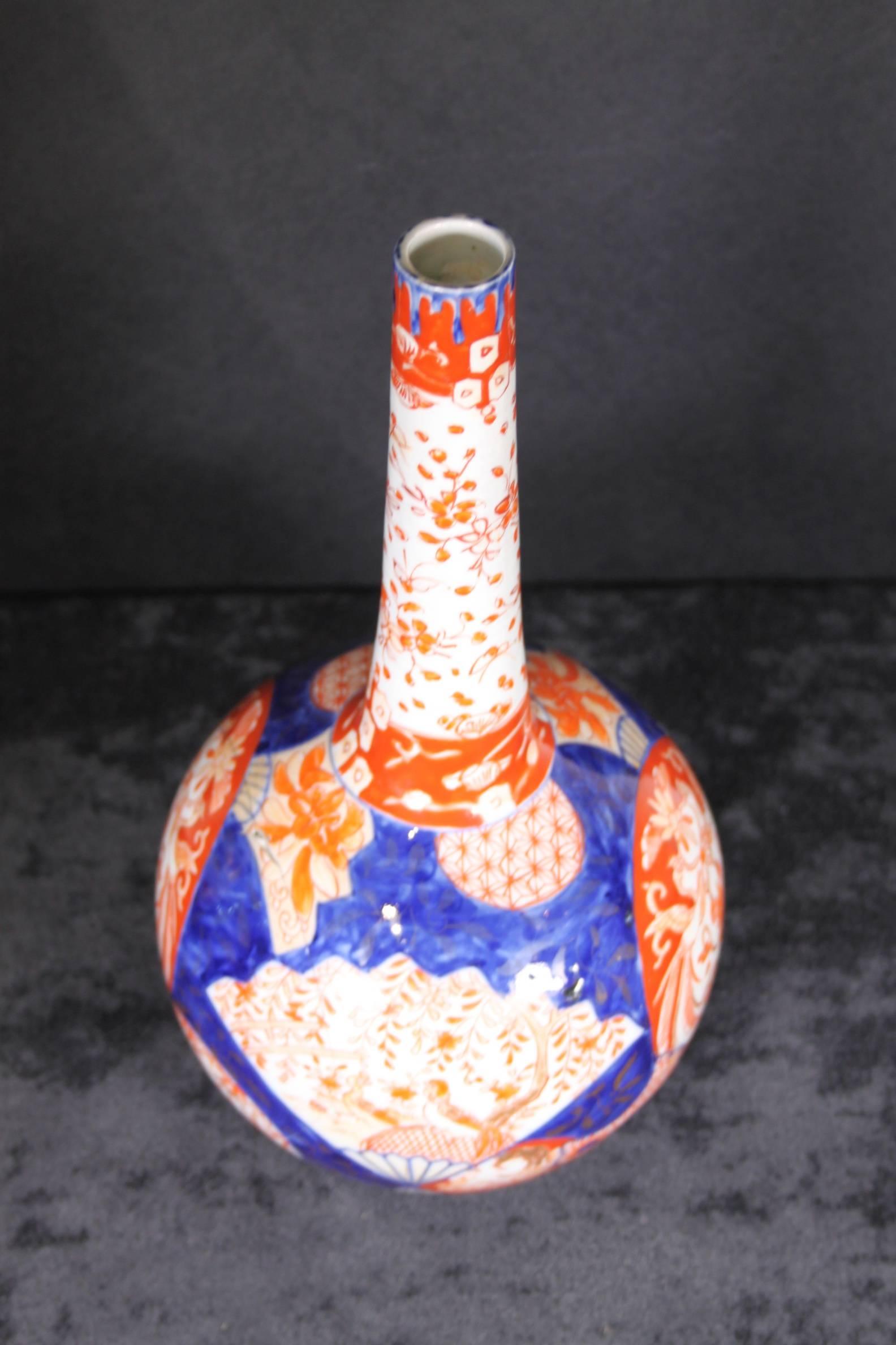 Japanese porcelain globe base vase decorated in the Imari style color palette, circa 1870-1890. Condition: Crack exists between base and up on side. Appears structurally sound.