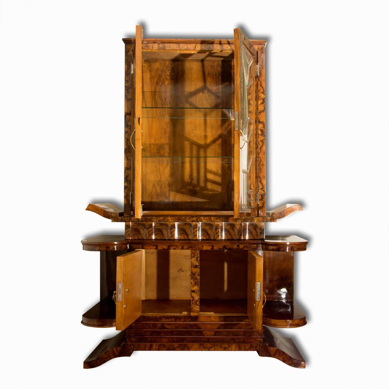 This Italian Art Deco showcase is veneered in walnut. It was designed and manufactured in the 1930s. The cabinet was designed in the context of the Italian pre-war design school. The cabinet has inlaid glass, rounded but also irregular edges. It