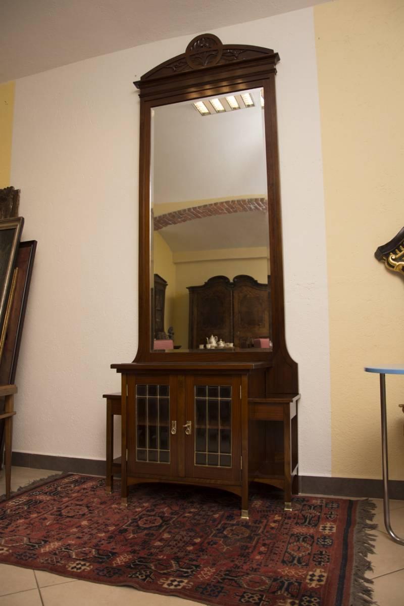 A large mirror with storage space from the Vienna Secession period. The mirror features geometric elements and shapes typical of Viennese Art Nouveau. It was manufactured in Austria-Hungary at the beginning of the 20th century. It is made of wood