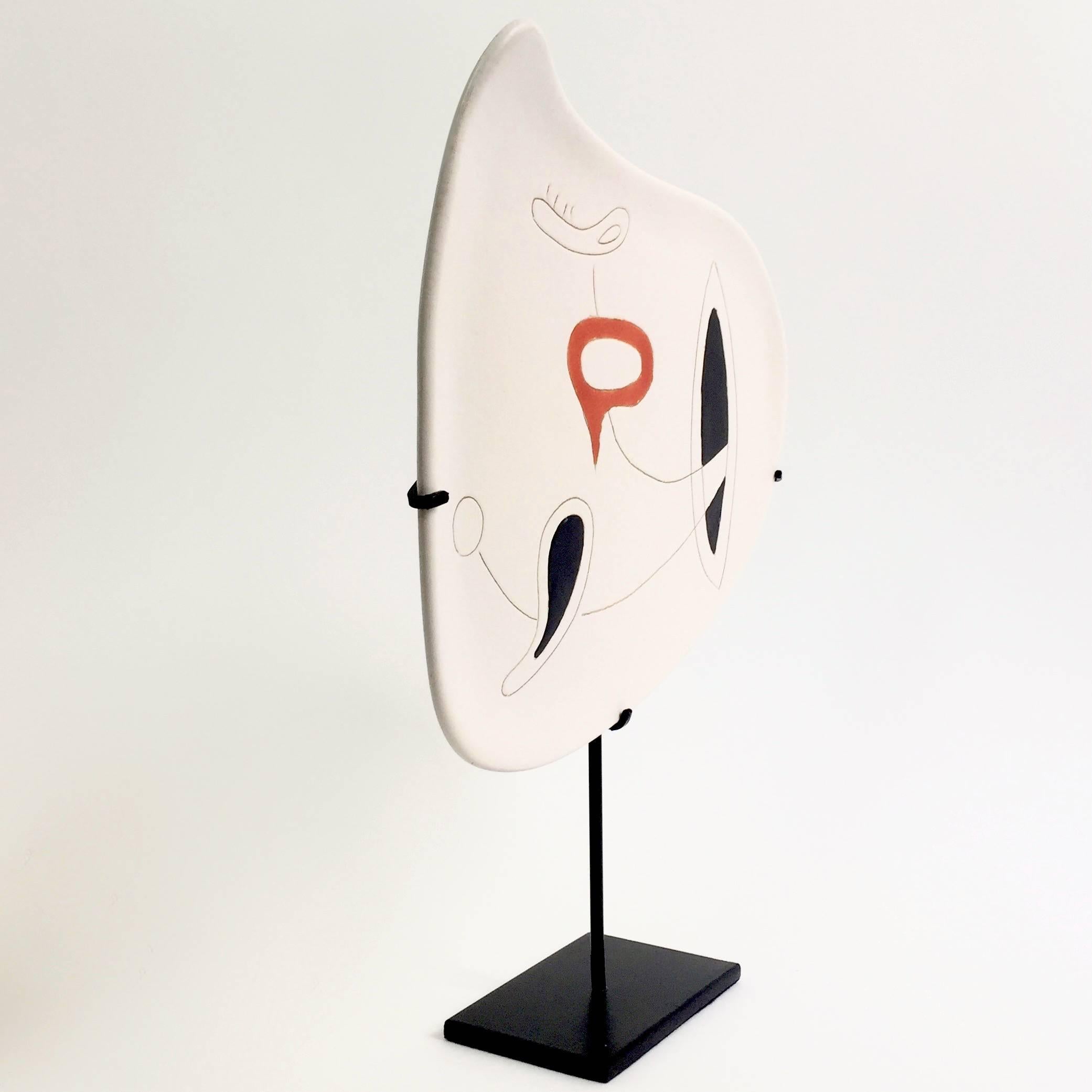 An organic shaped earthenware dish glazed in white with abstract and geometric decoration engraved and over-glazed in shinny black and orange-red. 

Typical Mid-Century Modern abstract and geometric design, reminiscent of Joan Miro´ or Calder