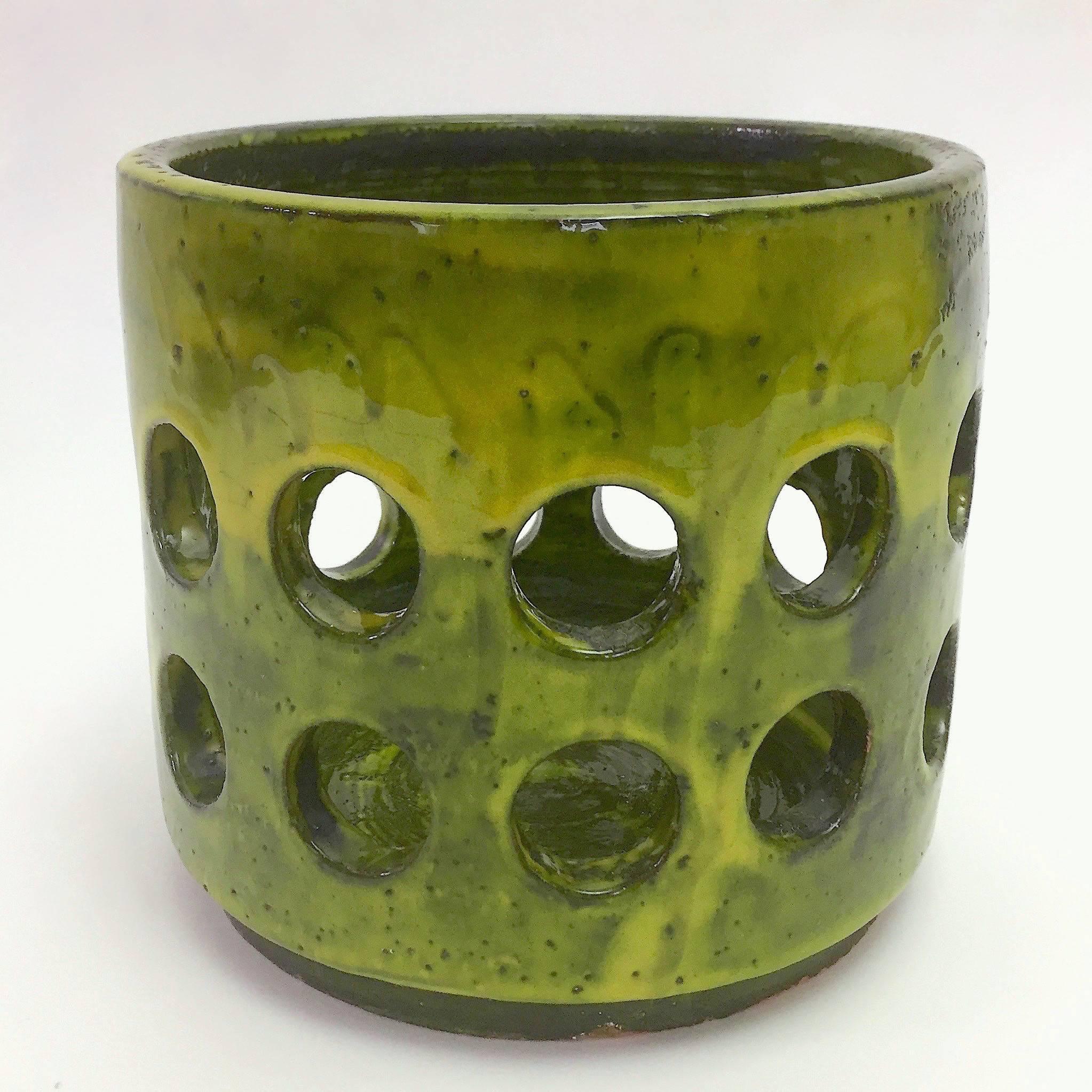 Important cylinder vase or cachepot, ceramic glazed in shades shiny green, and decorated with perforated geometric circles. 

Rare artwork designed by the artist from the collection named Engrenages.
This piece unsigned but referenced in the book