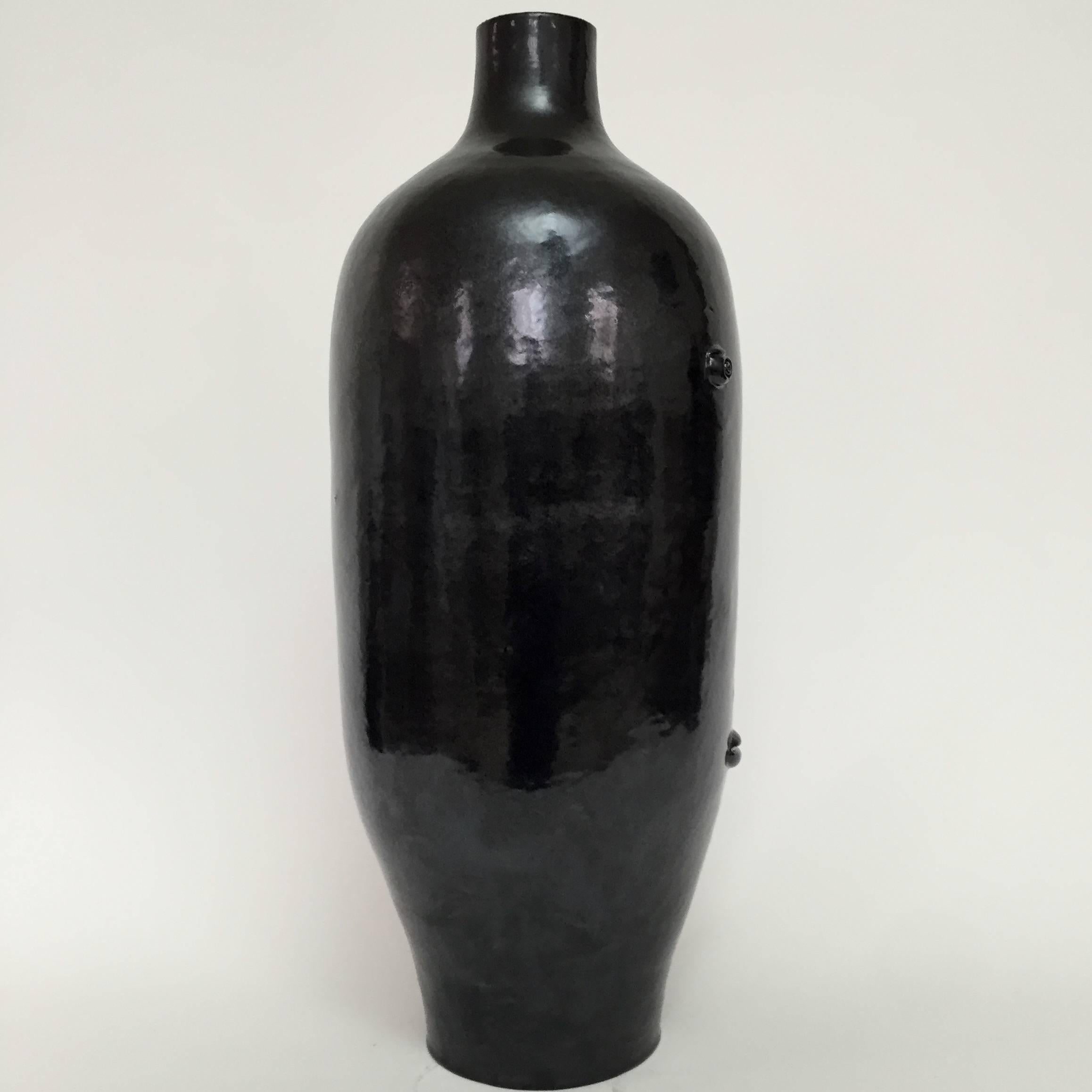 Important hand-made sculpture forming biomorphic lamp-base.
Stoneware glazed in glossy black, decorated with stylized visage sculpted and incised in front.
One of a kind ceramic piece designed and signed by the French ceramicists, Dalo. 

The