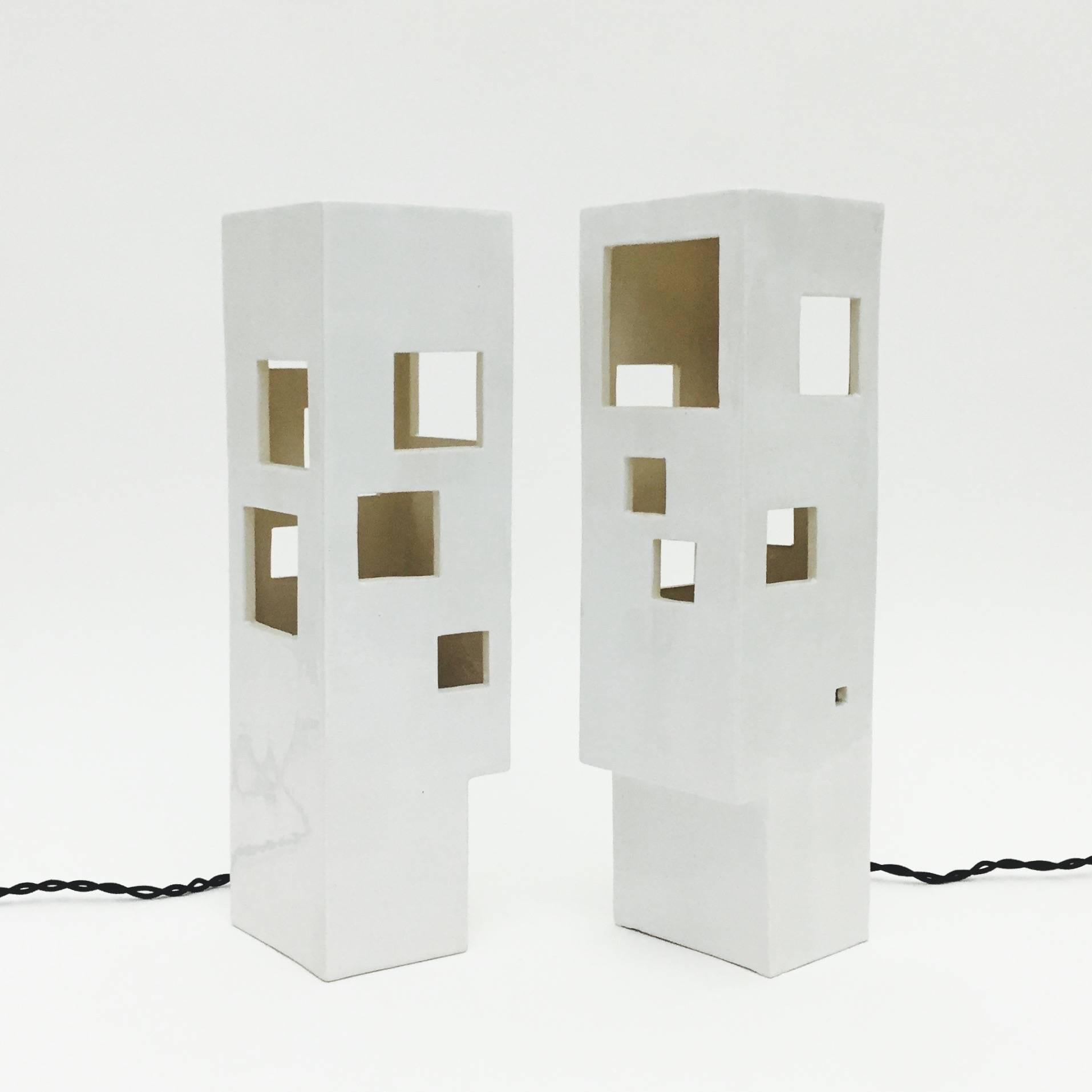 Architectural and geometric ceramic pieces, forming table lamps, hand-crafted and designed as a tribute to a modernist and Minimalist structure.

Ceramic partially glazed in glossy milky white, perforated with squares and rectangles cuts, light
