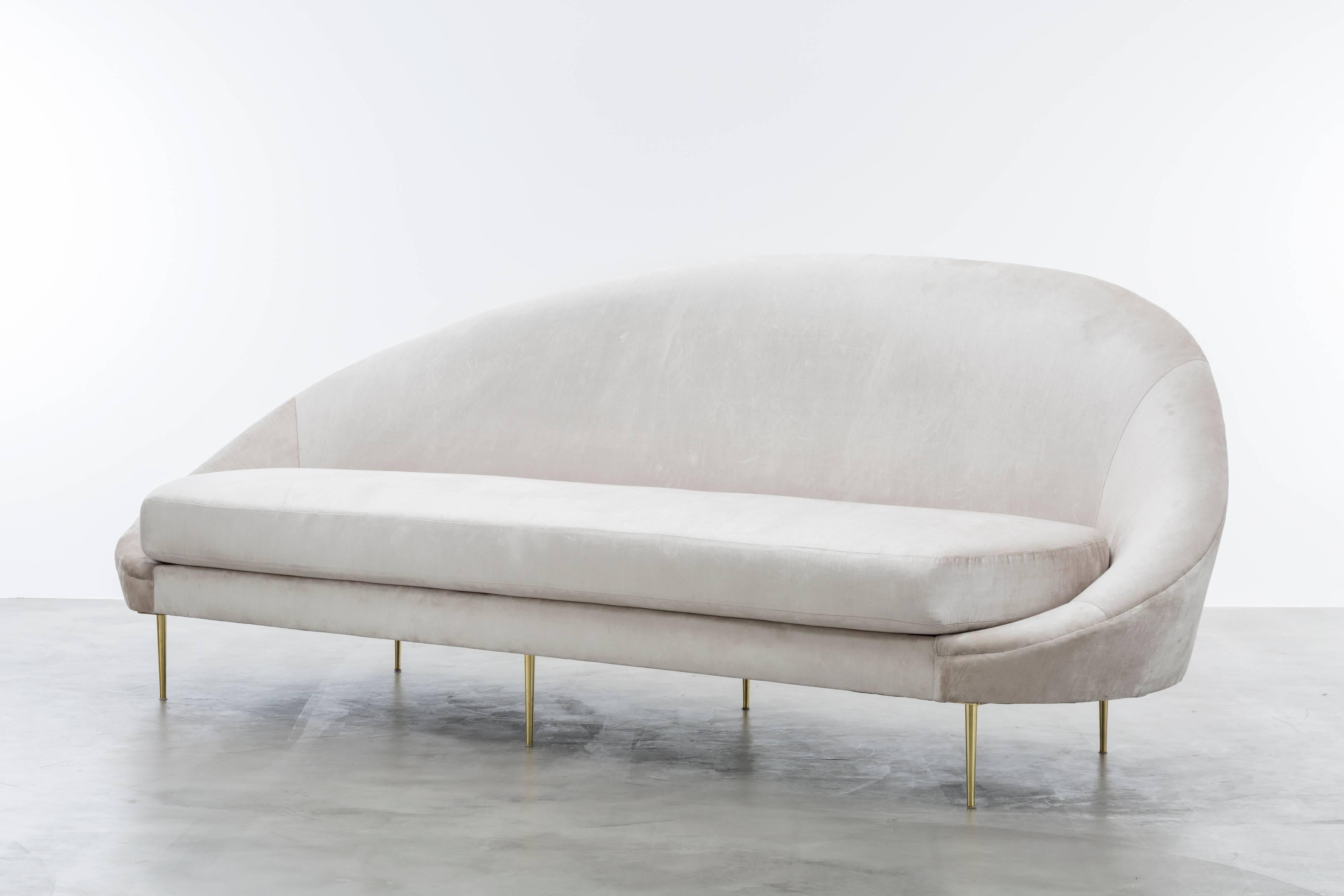SANDRINE SOFA - Moderner asymmetrischer Pergamentsamt mit Beinen aus massivem Messing

Das Sandrine Sofa ist ein wunderschönes Möbelstück, das von den Kurven der Gaudi-Architektur inspiriert ist. Das Sofa zeichnet sich durch eine asymmetrische und