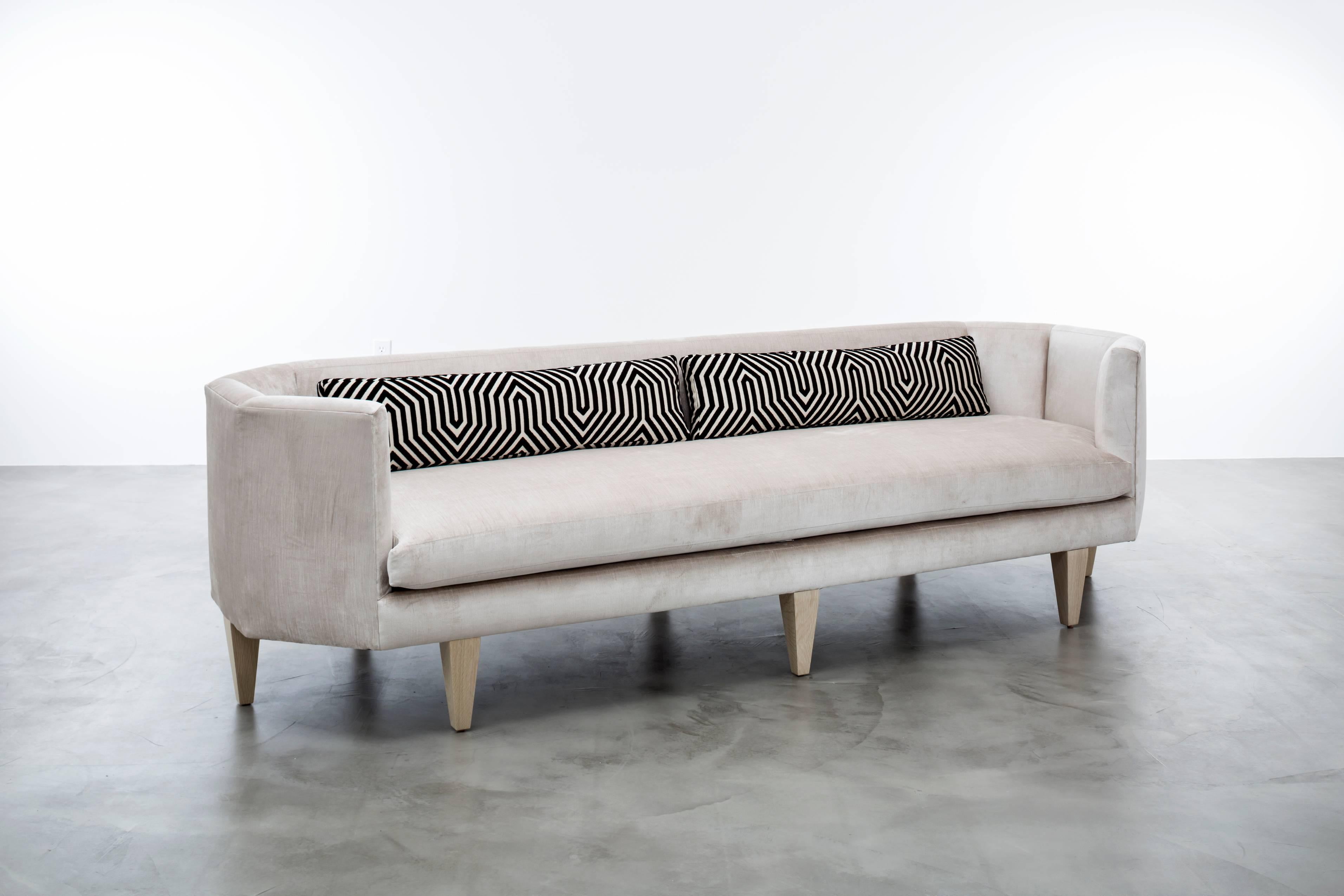 ODETTE SOFA - Modern Angled in Ivory Velvet with Oak Legs

The Odette Sofa is a stunning and unique piece of furniture that's sure to become the centerpiece of any room. Its octagonal-shaped upholstered velvet seat and back provide a comfortable and