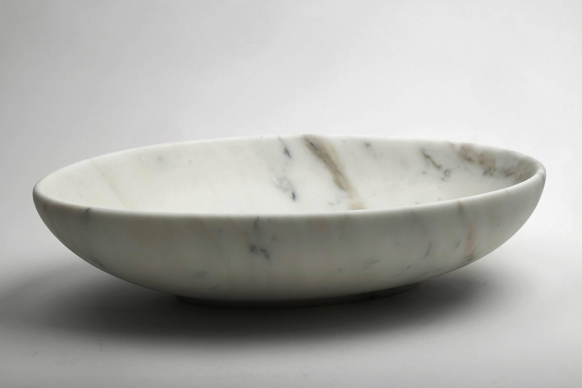 Big oval bowl in white Carrara marble. The object is a clean bowl without base. Each piece is in a way unique (since each marble block is different in veins and shades) and handmade by Italian artisans specialized over generations in processing the
