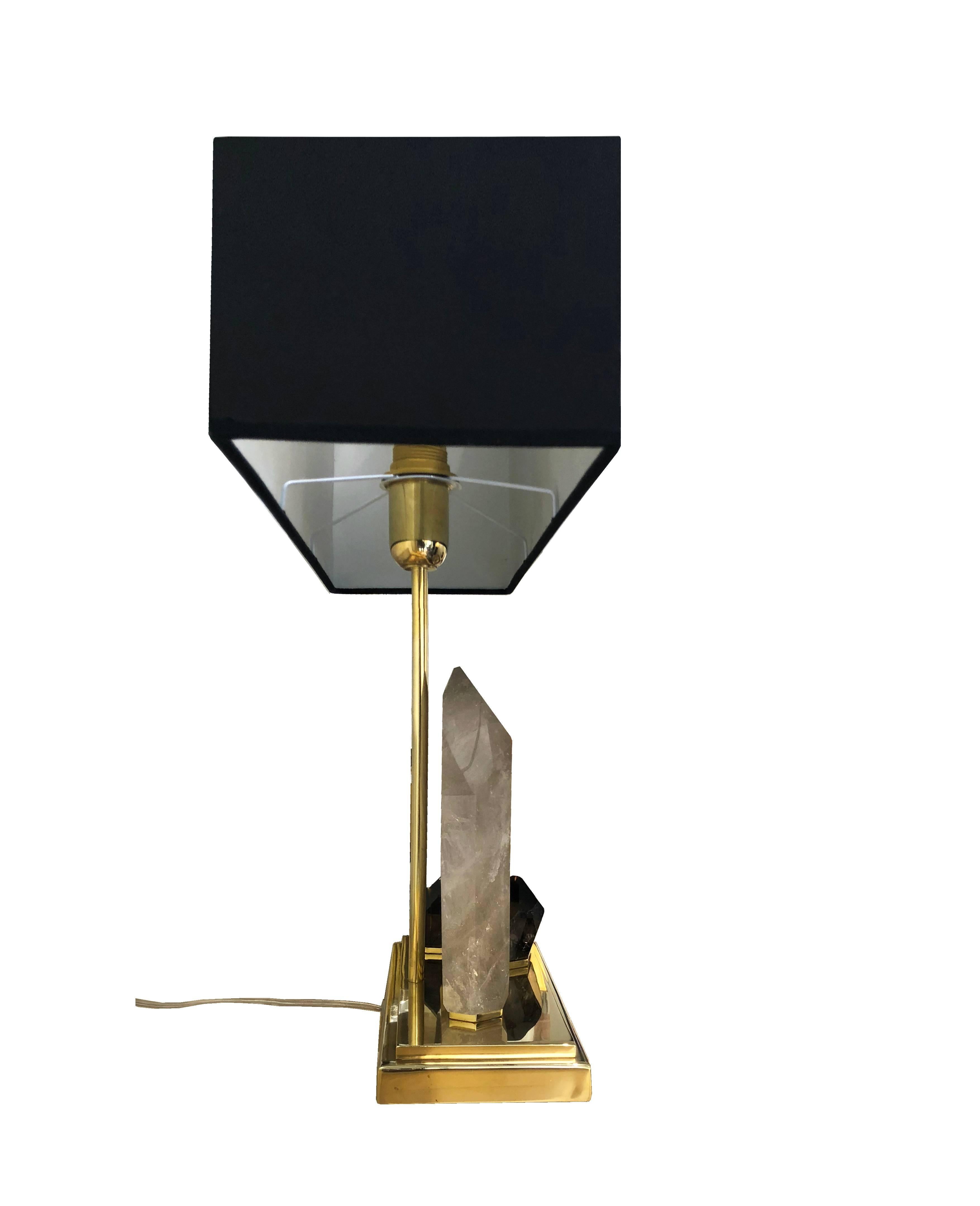 Stunning midcentury style table lamp in polished brass and quartz stones.
On the rectangular base are nestled three quartz, the larger in fumè with beautiful brown shades and the smaller two in smoked dark grey color.
Each lamp is unique in its