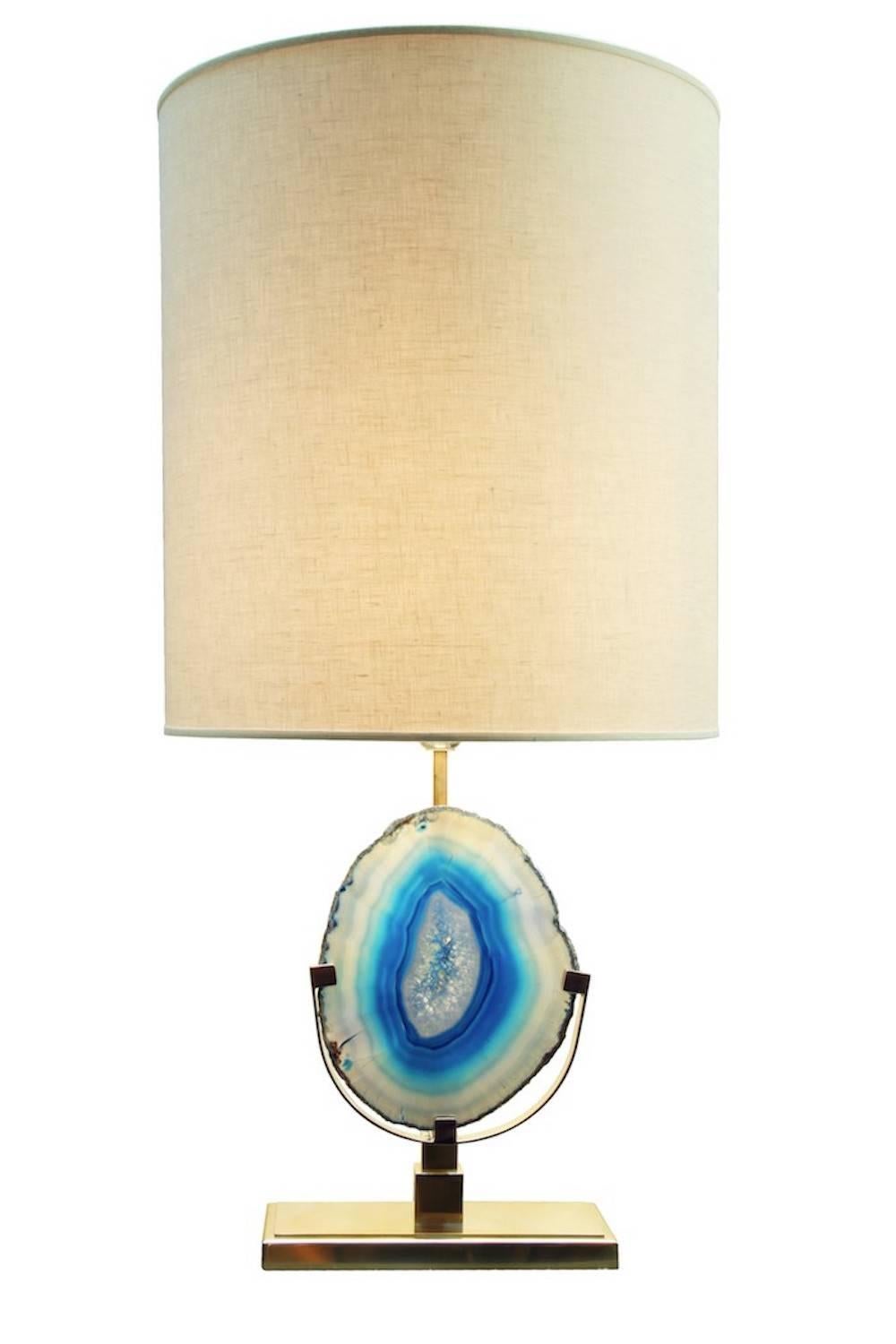 Pair of Agate table lamps in natural brass, lampshade in natural linen.
At the center of the lamp is placed a slice of agate stone, available in different colors. Each slice of this particular quartz since it's a natural element, is unique in its