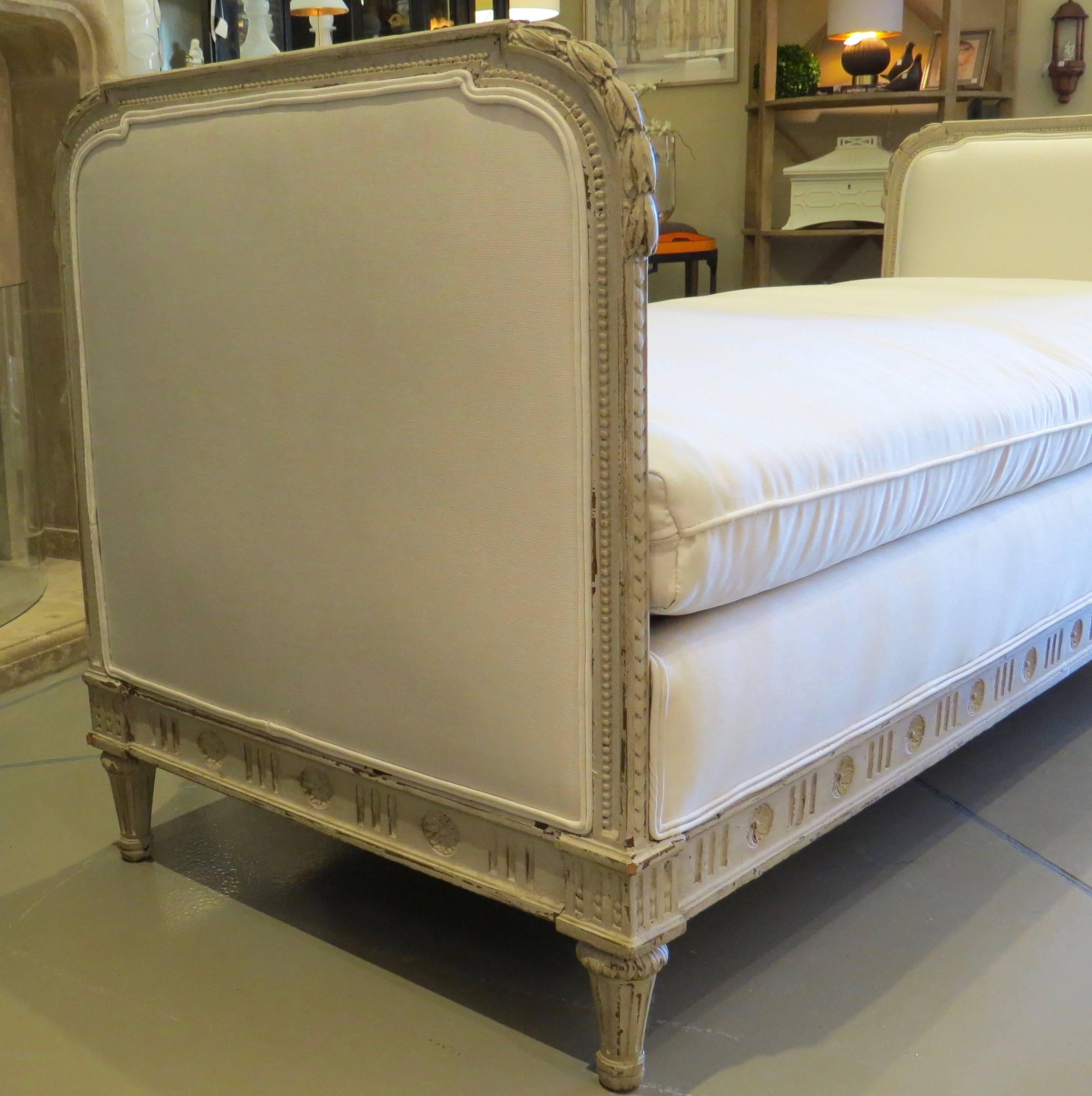 Daybed with new, white fabric upholstery. Carved and painted soft gray.
