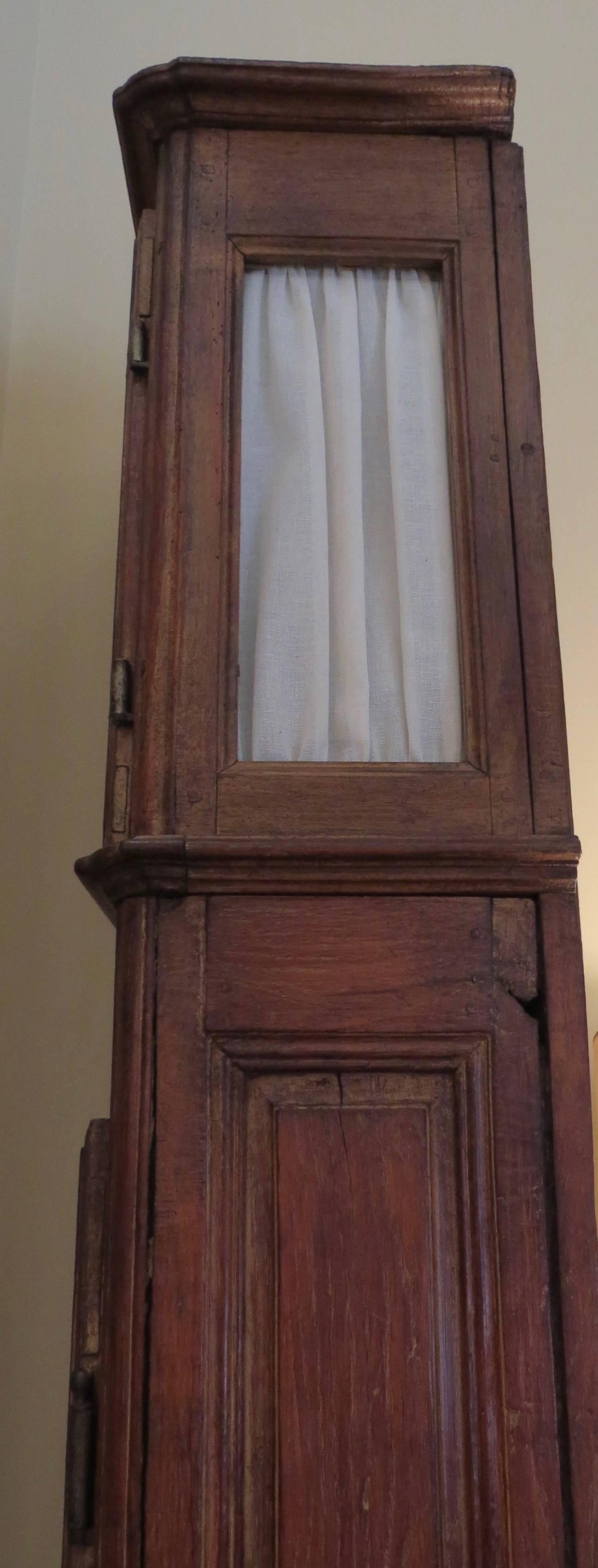 This tall, French oak clock case was made in the 19th century. A quartz movement and 20th century face with coq wreath adornment have been added. Fabric panels soften the glass windows on the sides of the clock housing. The front panel is a door