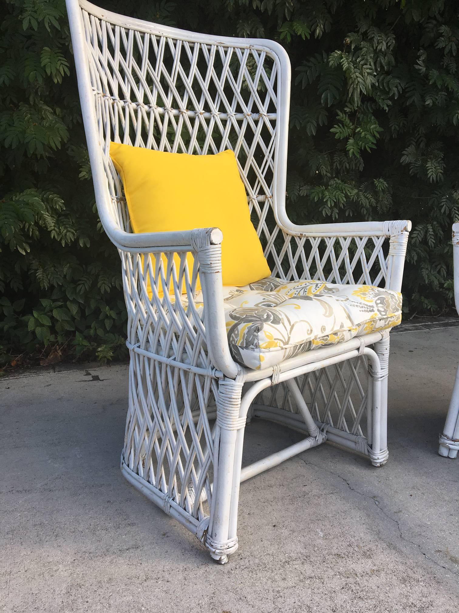 Pair of throne chairs in white wicker with bamboo and rattan framework. Definite statement pieces for any decor, indoor or out. Excellent structural condition with abrasions to the original white finish. Newer seat cushions and pillows in excellent