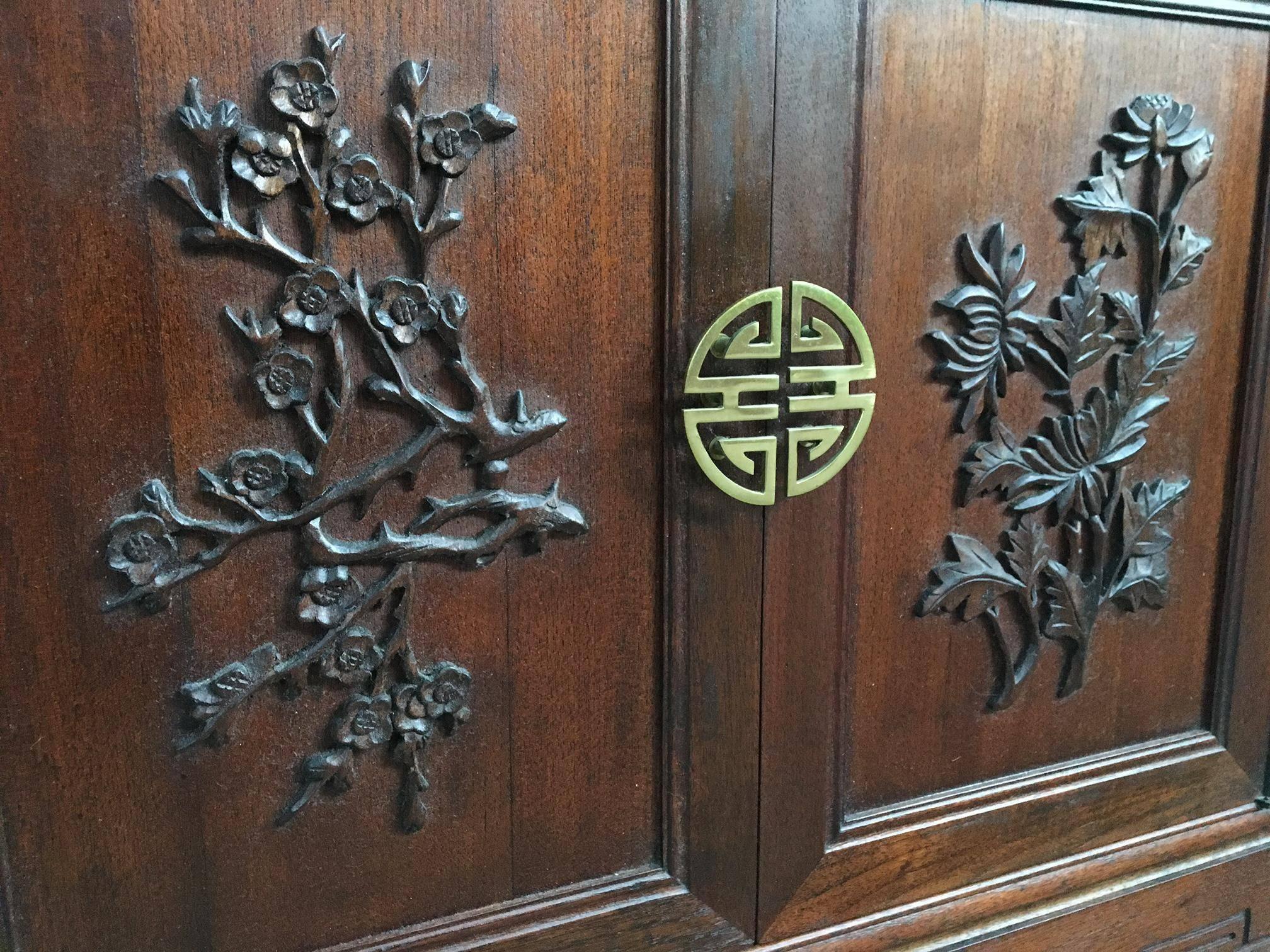 Chinese Chinoiserie display cabinet by Ricardo Lynn. Features detailed carvings of palm, bamboo and tropical trees. Stunning sculptural brass hardware. Excellent vintage condition.