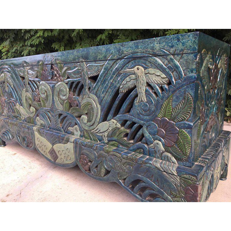 Intricate carving and hand painted detailing throughout make this one-of-a-kind chest a true statement piece. Solid wood construction on an elevated base with ornate hardware. Murals on top and inside featuring tropical birds and flowers by artist