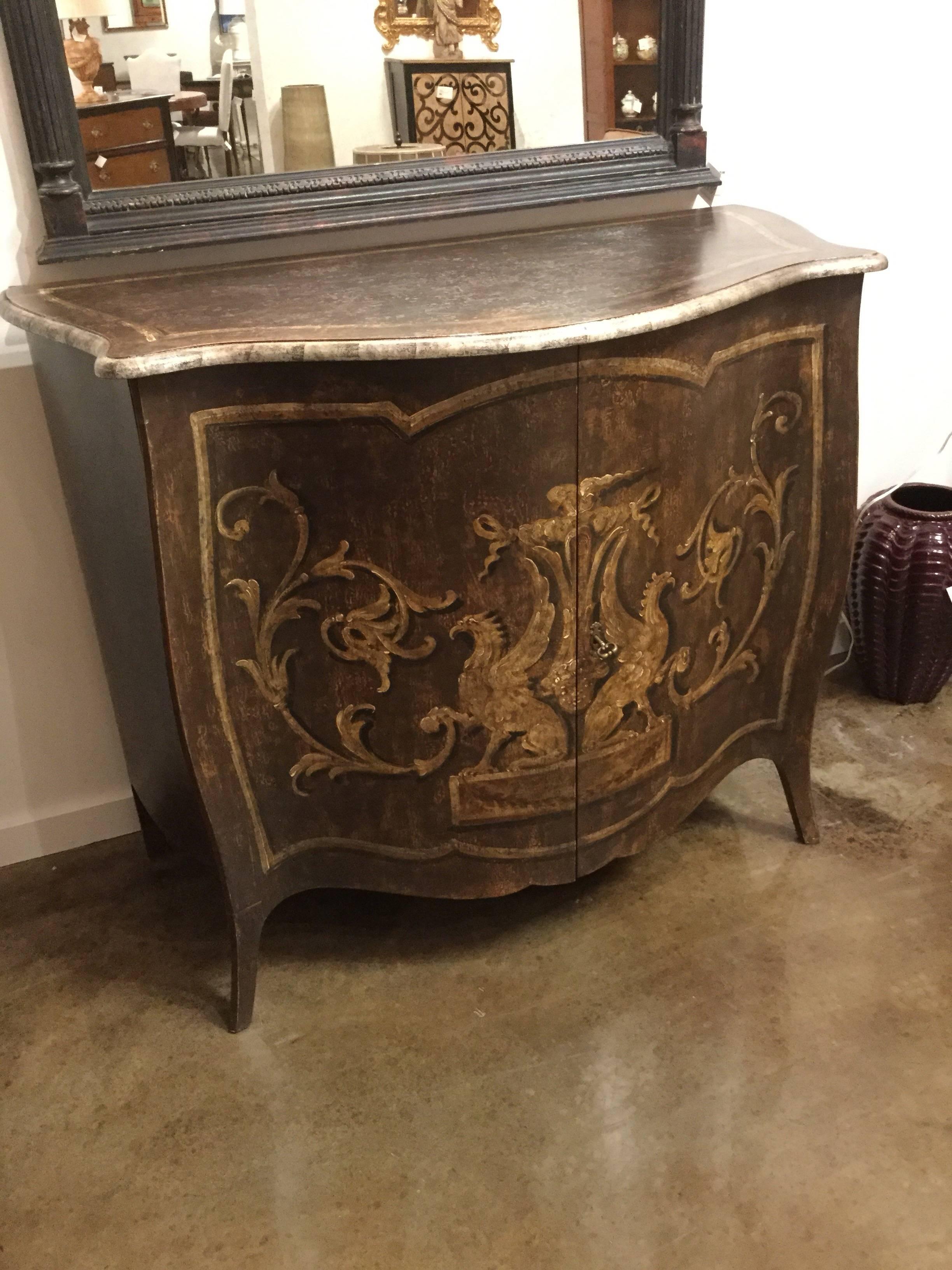 Hand-painted, two-door chest in an aged dark walnut color featuring griffons and scrolled vines on the bowed front in shades of ivory and gold, Italy.