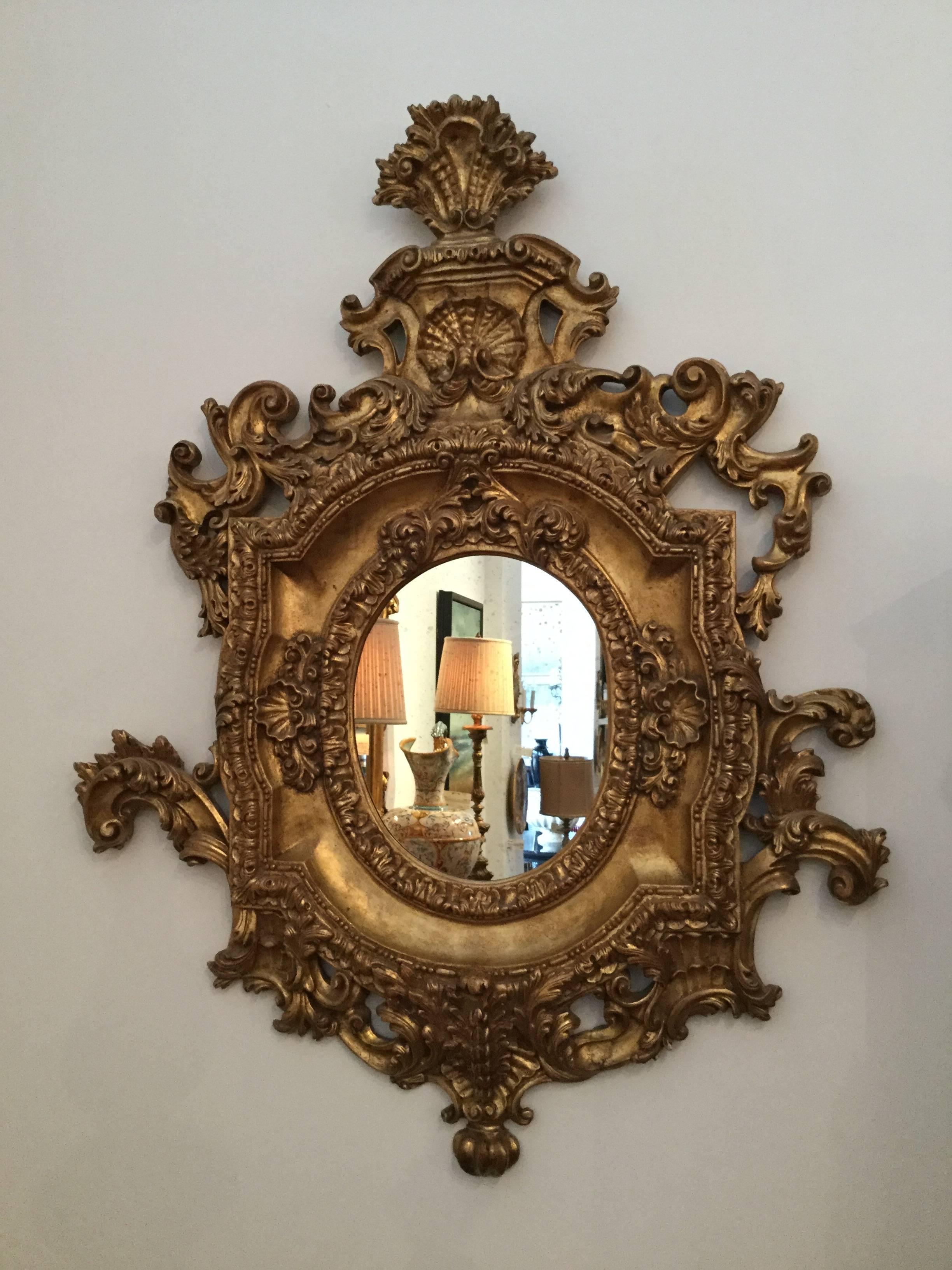 Hand-carved wood ornate mirror frame in an aged gold leaf finish with shell and plume motif.