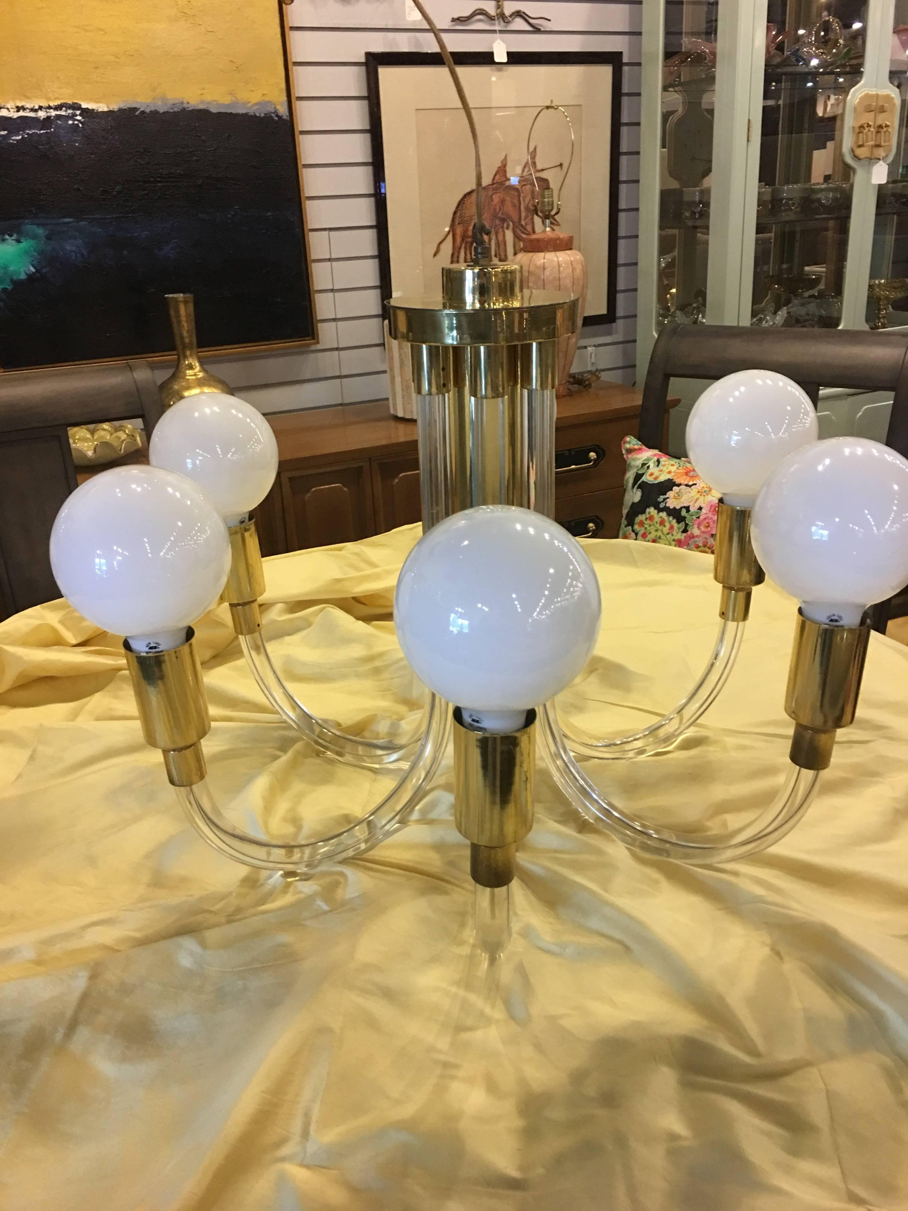 This stunning Mid-Century chandelier was designed by Charles Hollis Jones and hails from the 1960s. This piece has six Lucite arms that encase the wiring and curve to hold the brass fittings and the globe bulbs. It is in excellent vintage condition