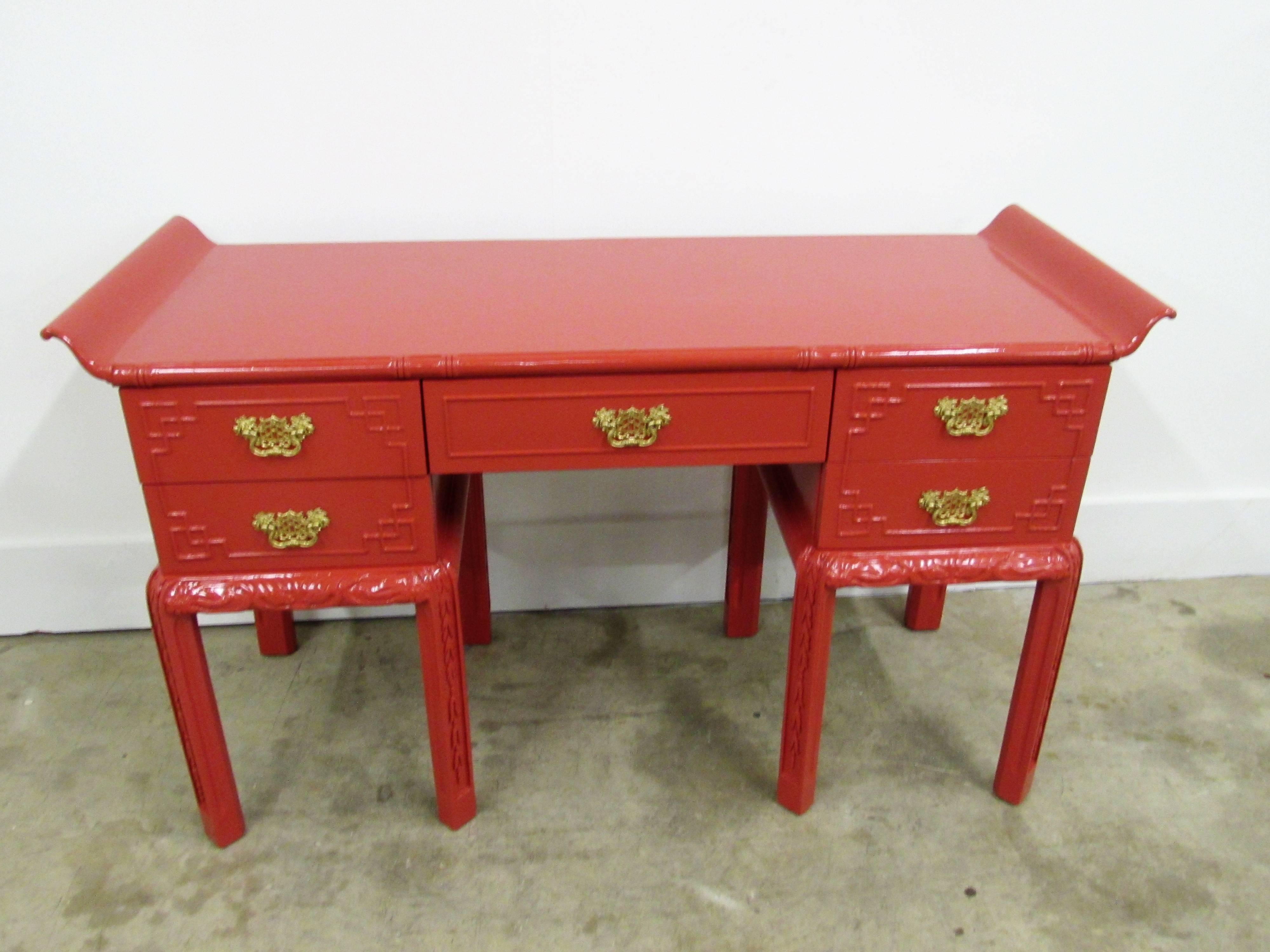Red lacquered mahogany chinoiserie pagoda desk or console table with five drawers and fretwork design on drawers with amazing pagoda brass hardware, sitting below eight intricately carved legs. Floor to bottom of middle drawer; 23