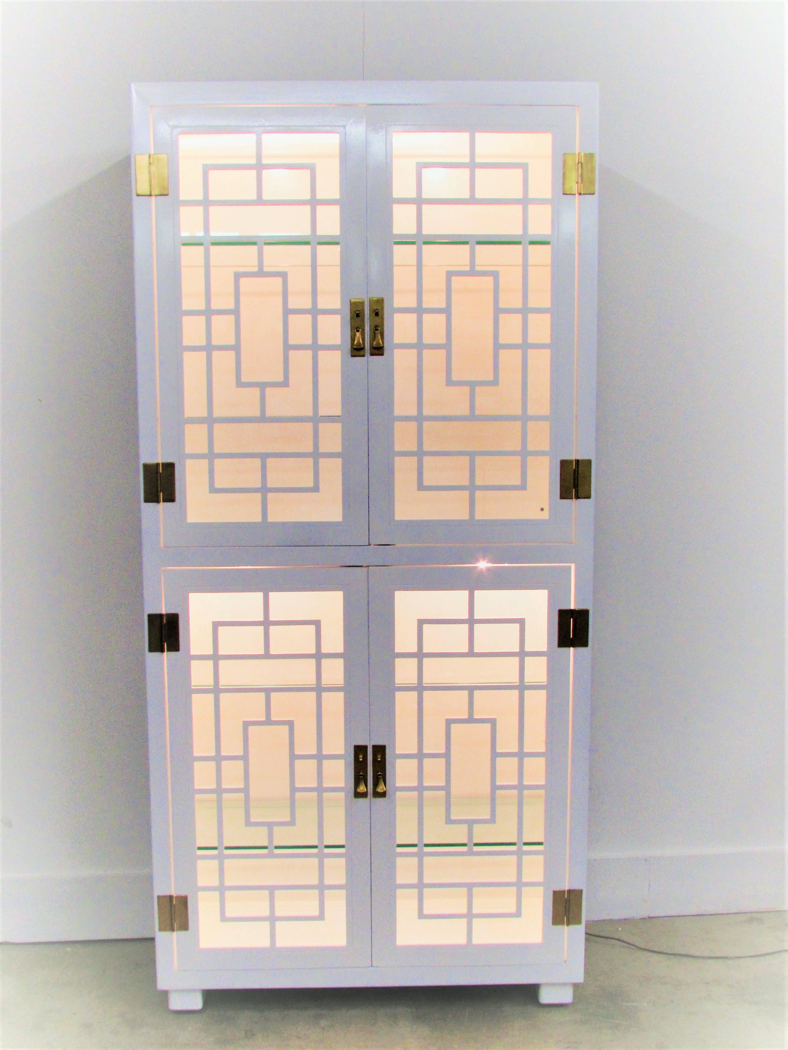 Chinese Chippendale etagère customized in white lacquer with four swinging doors and four 3/8 glass shelves, it has two lights on the bottom and
two lights on the top.