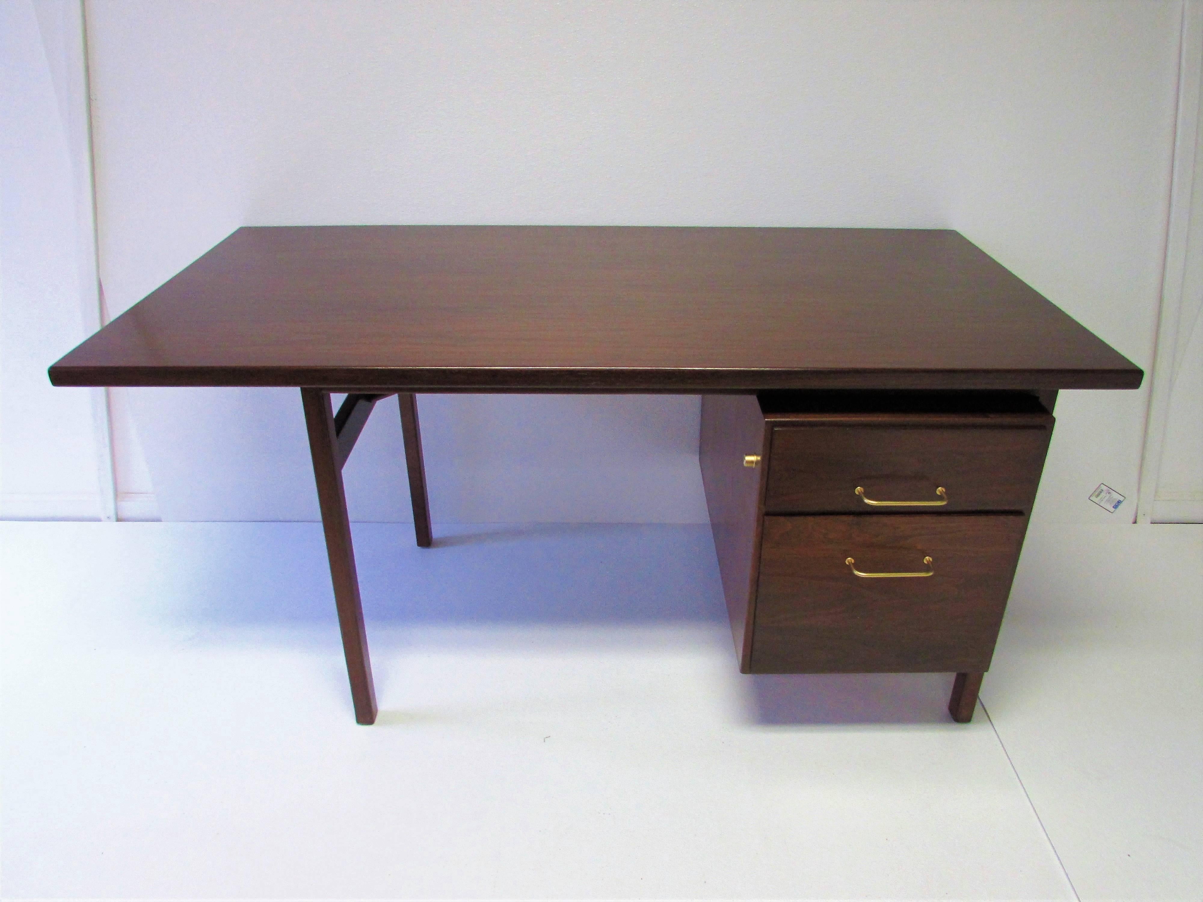 Refinished walnut desk with floating top, two drawers, and original brass handles attributed to Jens Risom.