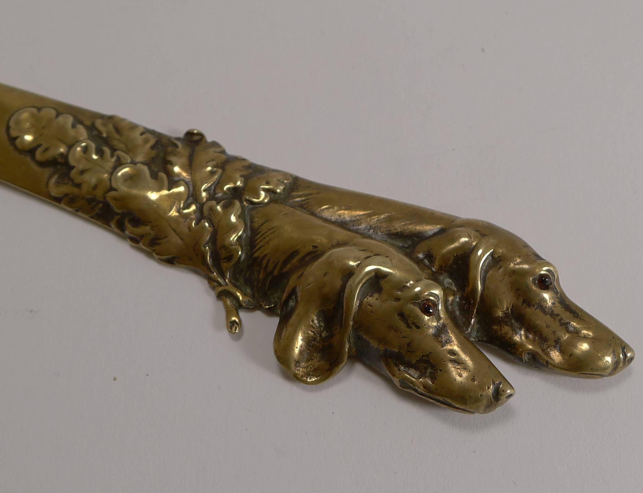 A fabulous desk-top accessory, this solid cast brass letter opener dates to circa 1900, with the makers mark stamped on the underside, I have not been able to identify the manufacturer.

Beautifully cast, the handle is formed by two handsome dog