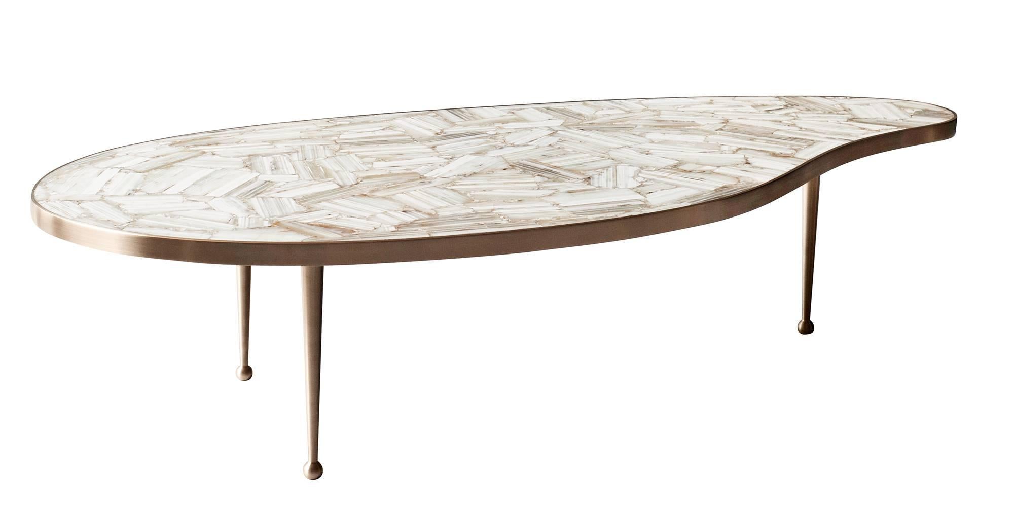The bio-morphic shape and clean lines of the Lola coffee table by DeMuro Das were inspired by midcentury design. With a stone top made of polished, hand-laid creamy white agate, the table surface is both luxurious and functional. Hand-cast, solid