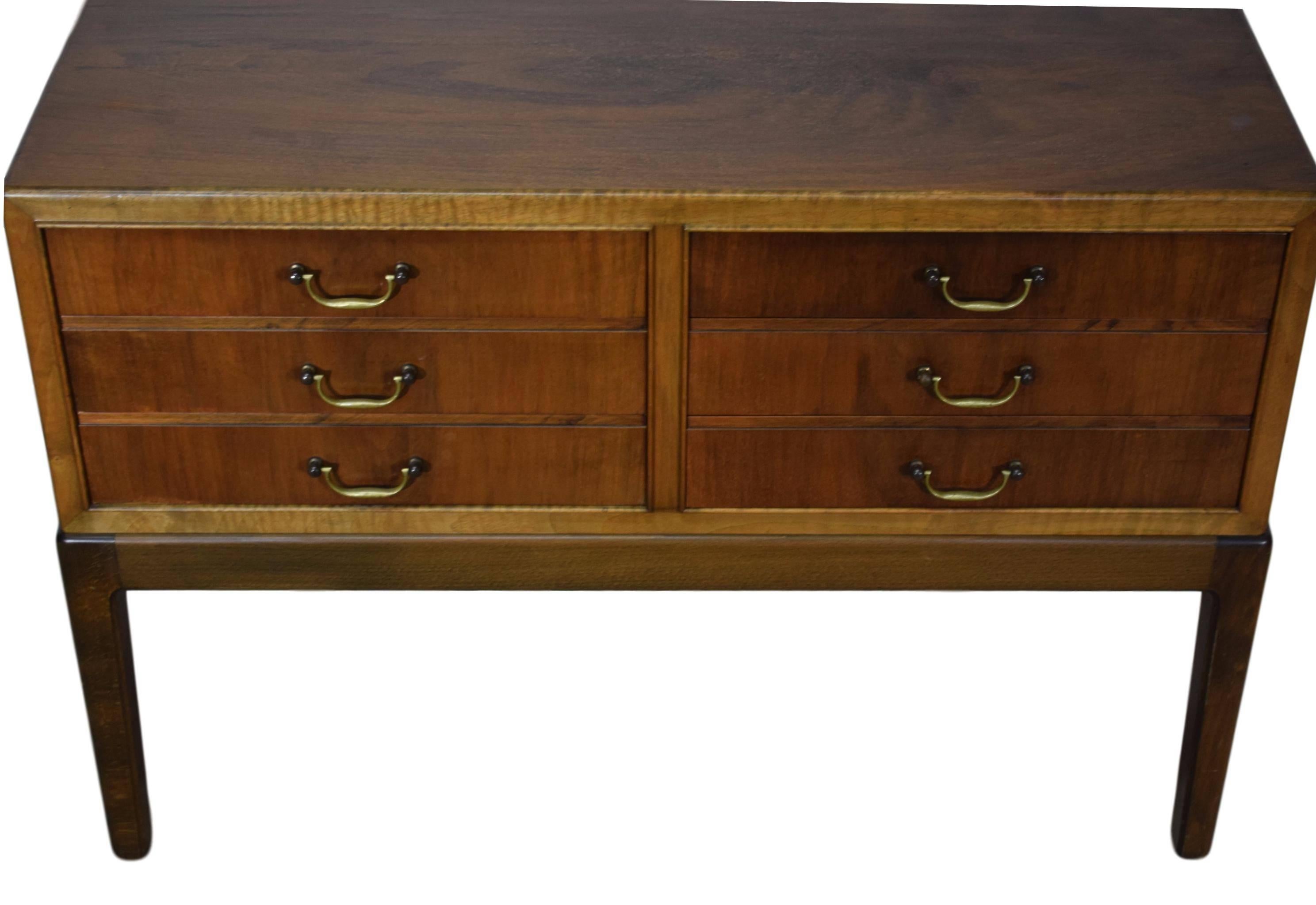 An early Danish midcentury walnut dresser with brass handles by Ole Wanscher (1903-1985). Six drawers. Walnut veneer and stained beech frame.

 