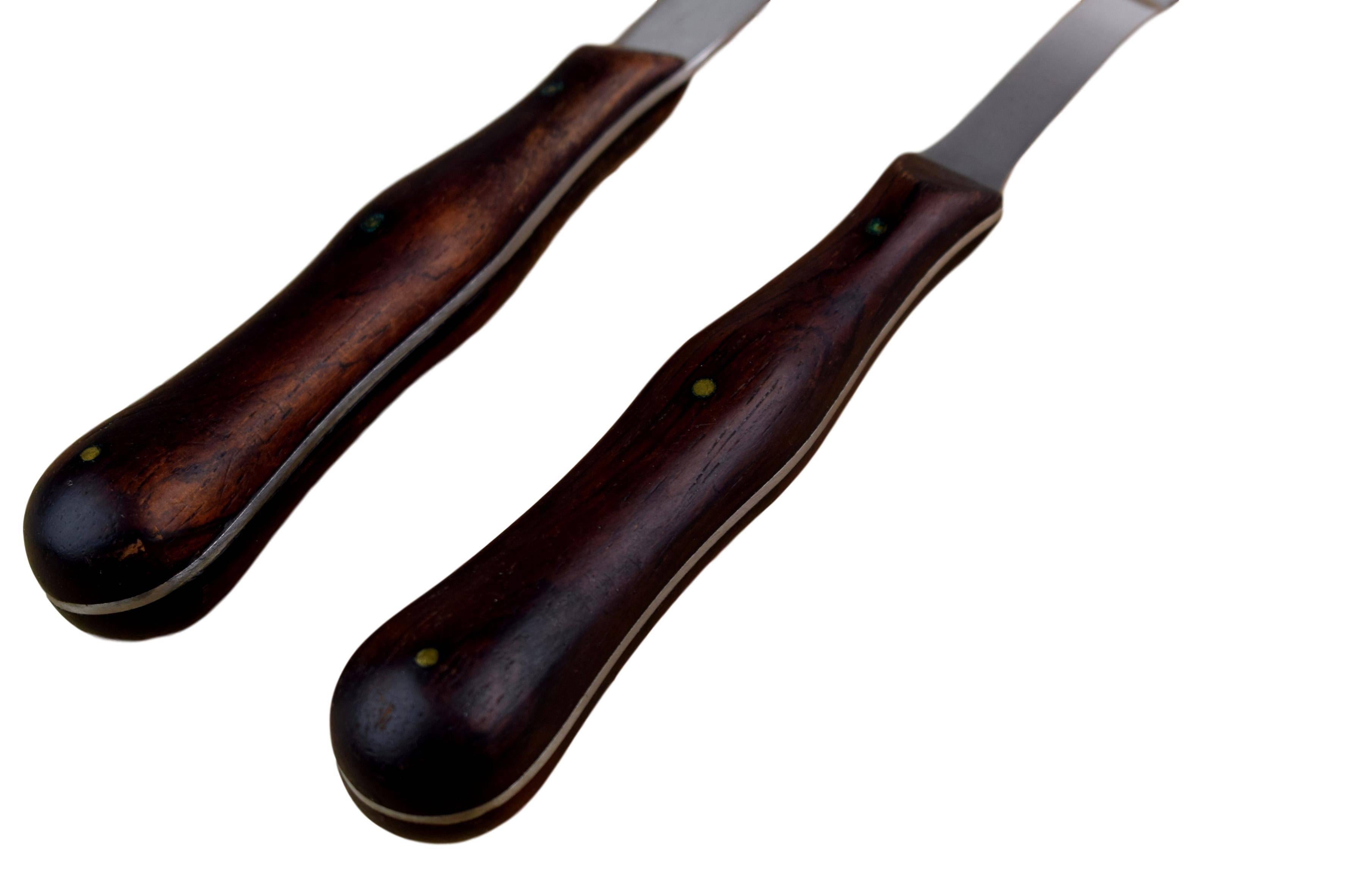 A Danish midcentury carving knife and fork by Kay Bojesen (1886-1958). Rosewood handles. Produced by Universal Steel Company, Copenhagen. Marked 
