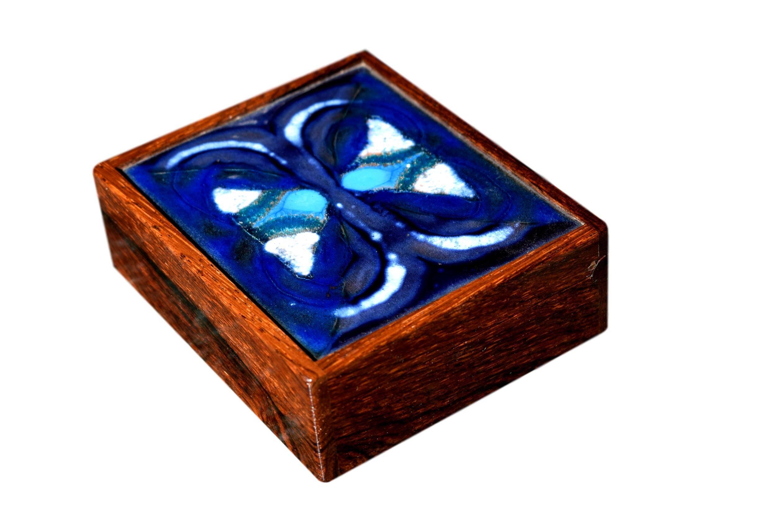 A Danish midcentury rosewood box with hidden hinges by Alfred Klitgaard with a decorative polychrome enamel by Danish artist Bodil Eje. 

Stamped 