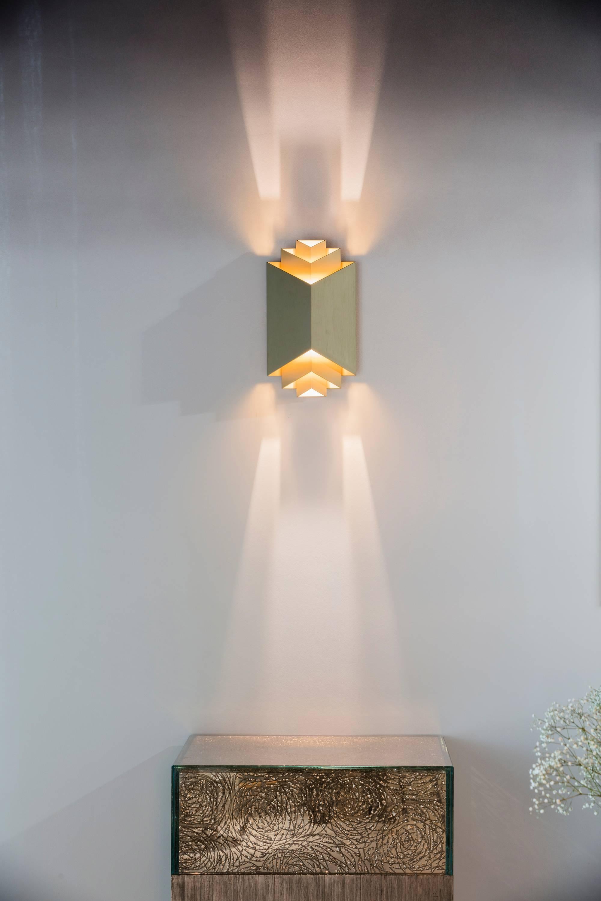 A historical wall light revisited by French architect and interior designer Joseph Dirand for Ozone. Aluminum and brass structure, gold finish. 

The lighting provides a very warm indirect light due to the reflections on the gold plates. LED sources.