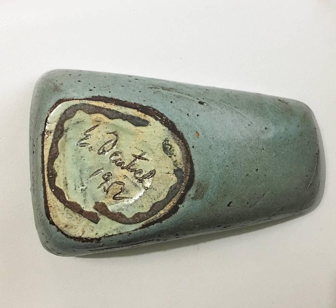 This midcentury 1952 Eugene Deutch piece ashtray features a glazed green inside, and black rough painted exterior. Four indentions in the top of the piece suggest that it could be used as an ashtray. The bottom of the piece features a light blue and