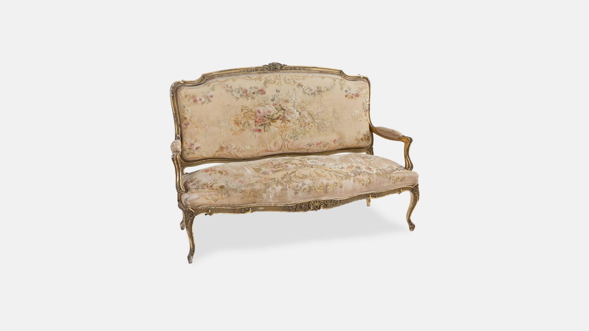 A beautiful antique carved giltwood Aubusson salon settee carved with rocaille and scallop shells on cabriole and scrolled feet.

Upholstered in a beautifully aged floral tapestry.