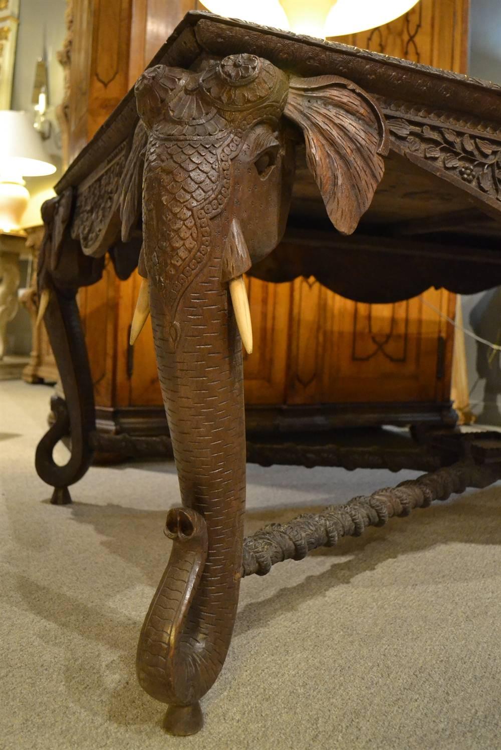 This late nineteenth century piece is intricately carved in teak with top carvings and details on all 4 sides. Its deep aprons connect to nicely carved elephant supports connecting to a center platform with serpent twist stretchers. The piece is in