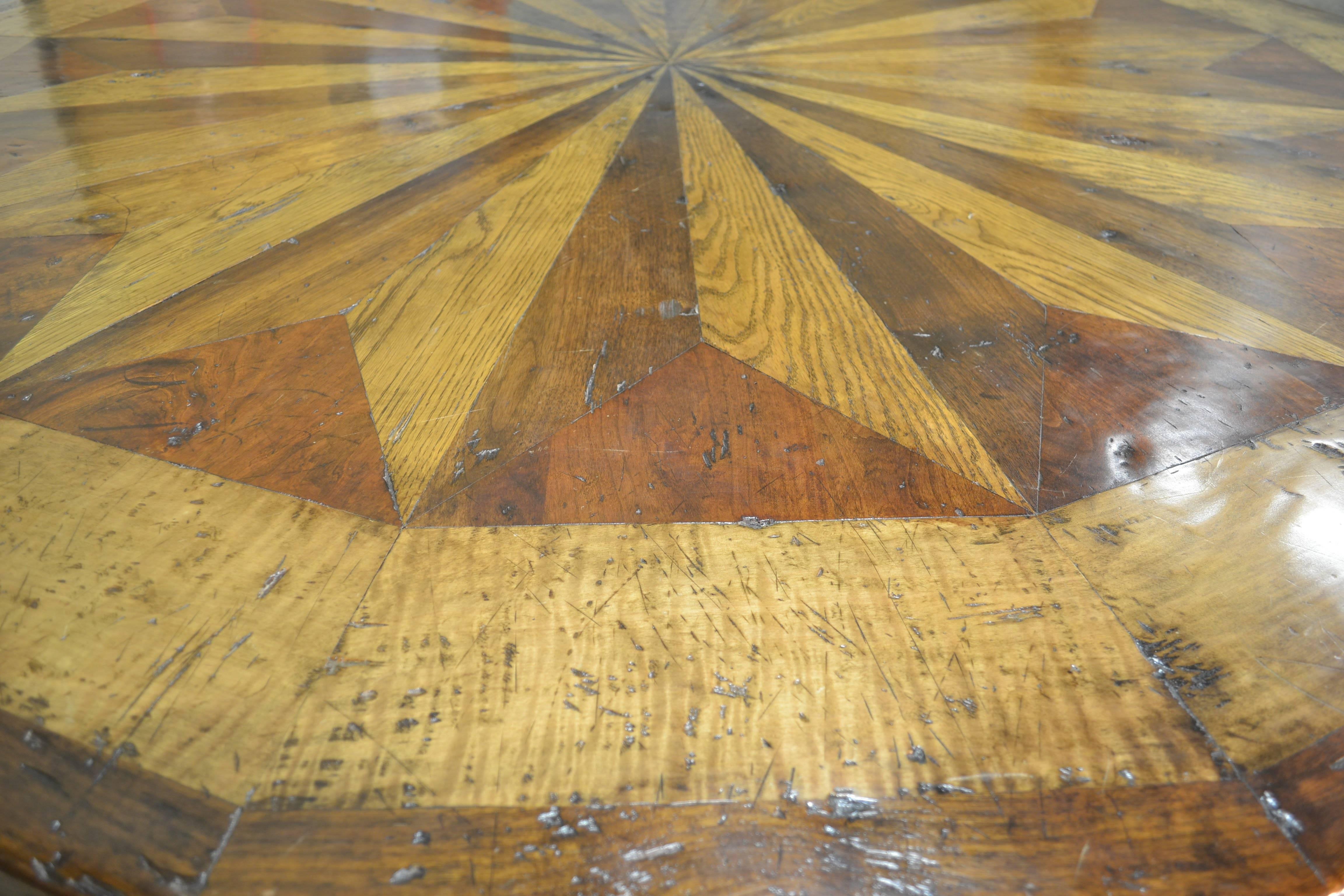 This table is the first pThis tabletop is composed of inlays of solid cherry, maple, oak, and walnut. The outer band is walnut and the base is carved mahogany with a walnut color.
 