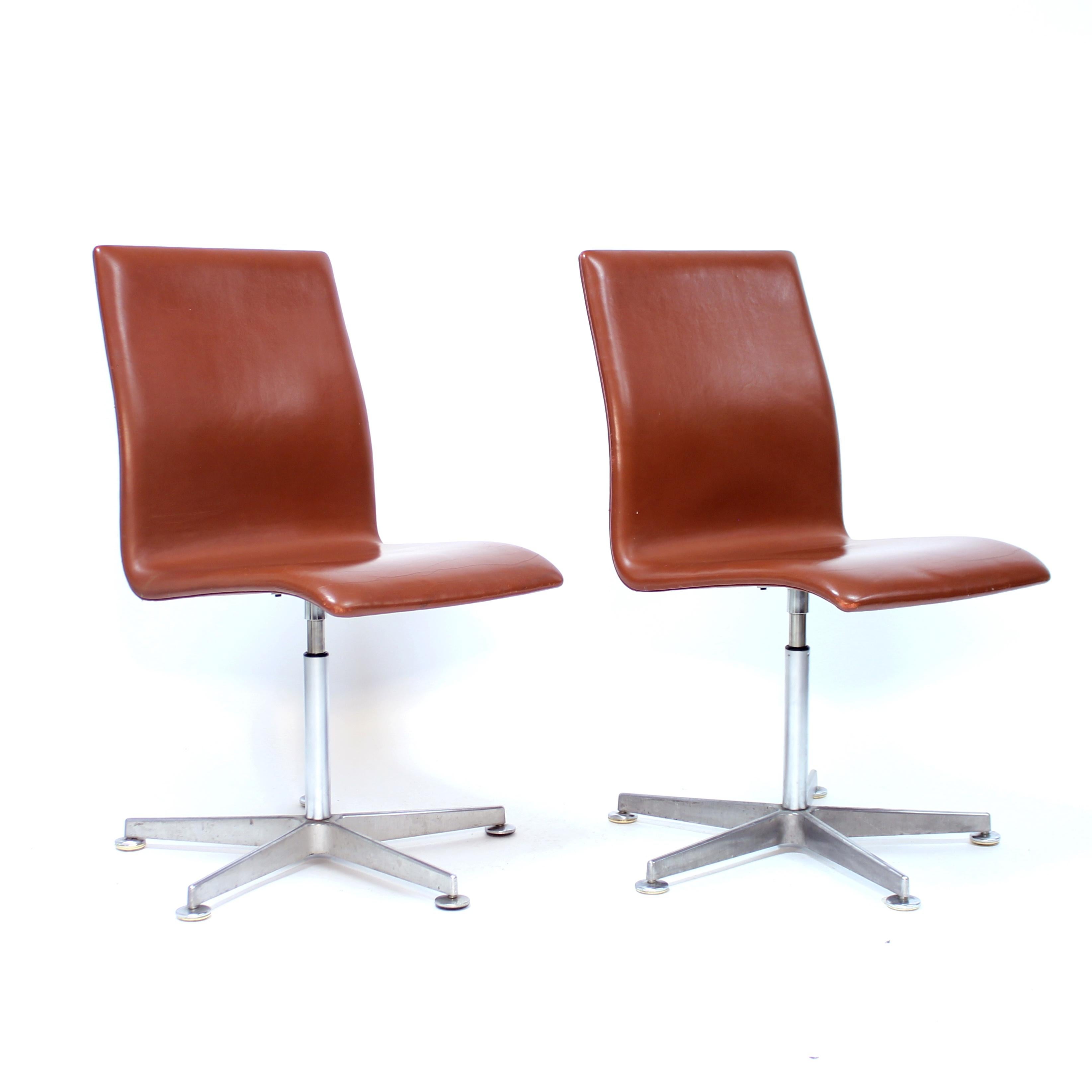 Paire de chaises Oxford conçues par Arne Jacobsen pour le collège St. Catherine de l'université d'Oxford en 1965 et produites par Fritz Hansen. Ces deux exemplaires ont été produits en 2005 et sont marqués d'un autocollant. Assise et dossier en cuir