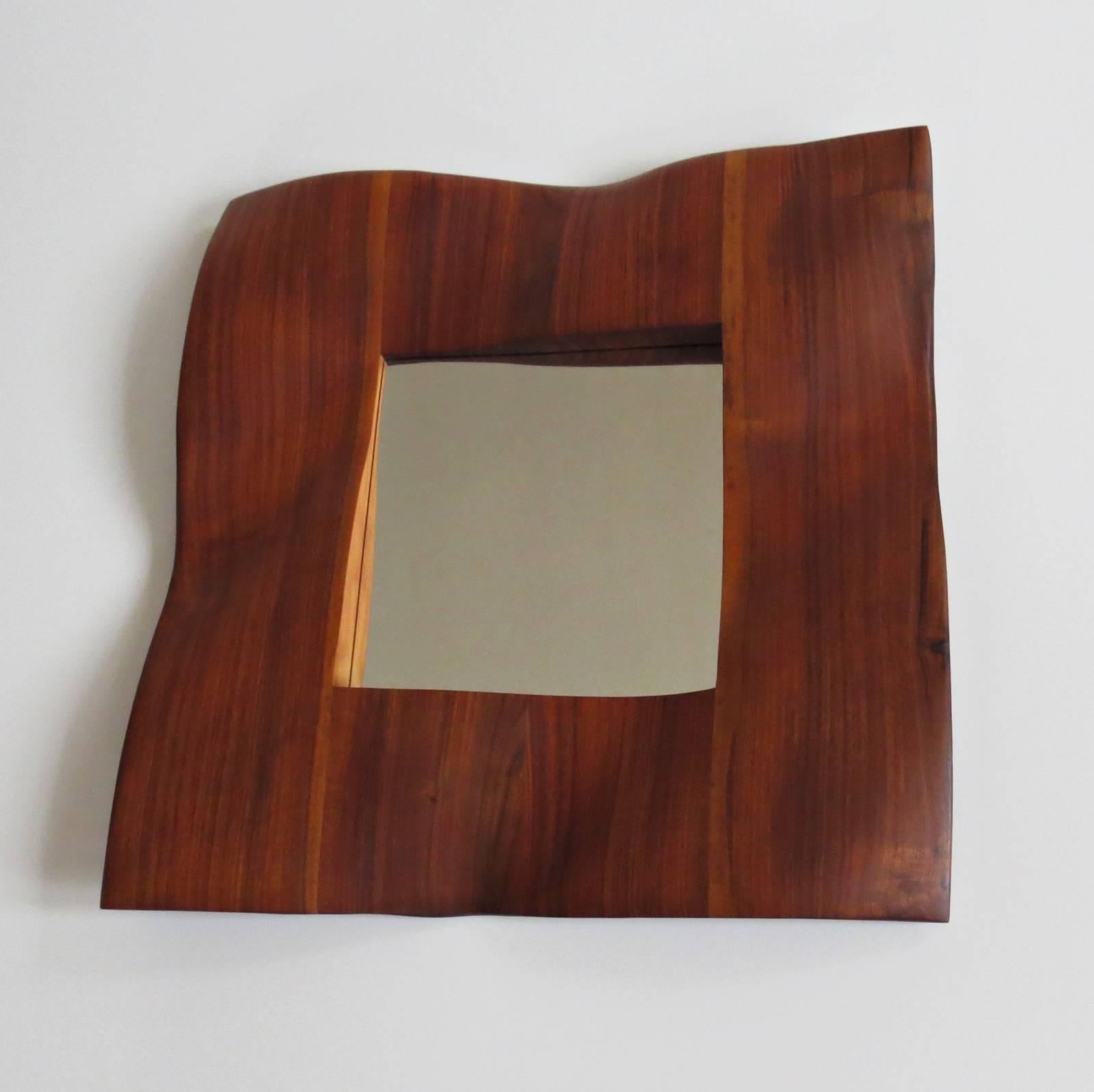 Solid wood mirror by German designer and sculptor Eckehard Weimann.
The frame is organically worked out like a wave.
He hangs on the wall like a sculpture and casts beautiful shadows.
Frame size is about 55 x 55 cm, mirror itself is about 25 x
