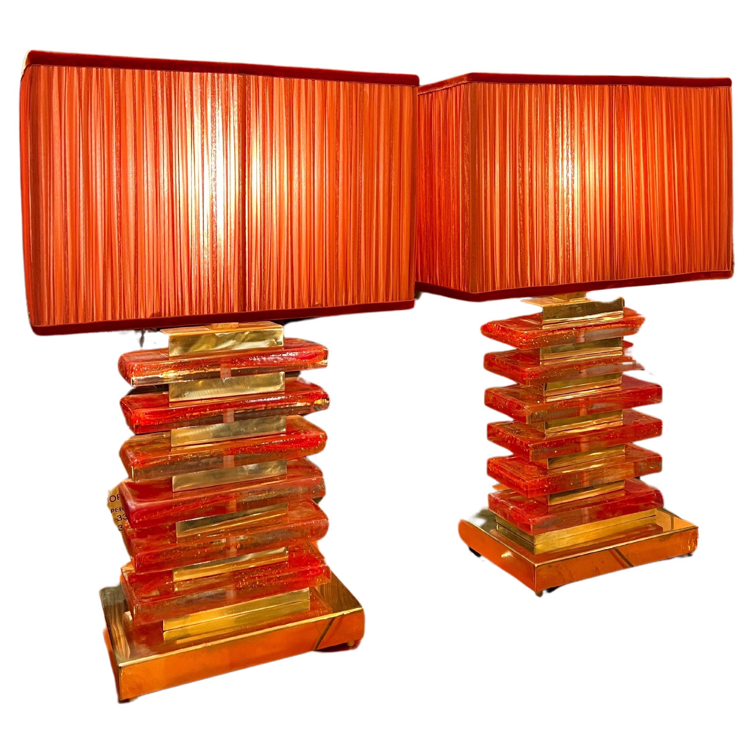 Coppia di lampade in vetro di Murano arancio e ottone presentate con nostri paralumi increspati a mano in chiffon di seta arancio. 
I blocchi di vetro di Murano arancio sono soffiati a mano con vetro di Murano trasparente creando un effetto