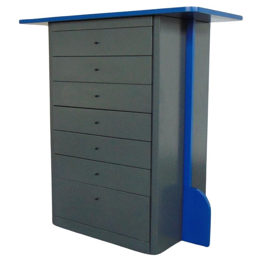 A one-of-a-kind gray Memphis style dresser with seven drawers, and a China blue top and side wings. Small black handles complete the piece.
It was designed in the late Eighties by Marco Comolli and Gabriella Poli for Sormani, following the taste of