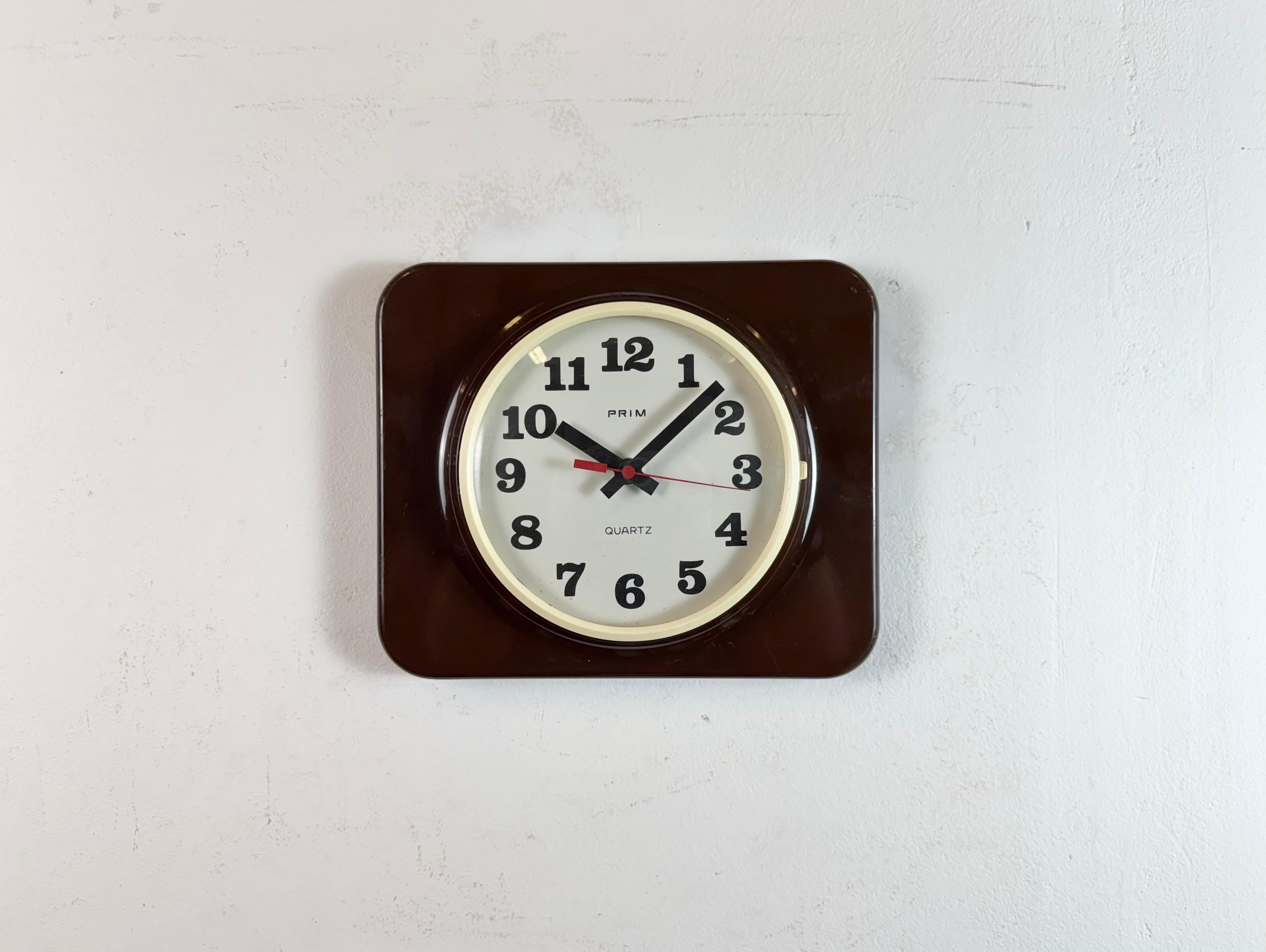 Vintage Bakelit Wanduhr wurde von Prim in der ehemaligen Tschechoslowakei in den 1970er - 1980er Jahren hergestellt. Sie hat ein braunes Bakelitgehäuse mit weißem Zifferblatt und einen gewölbten Klarglasdeckel. Das Original-Uhrwerk funktioniert