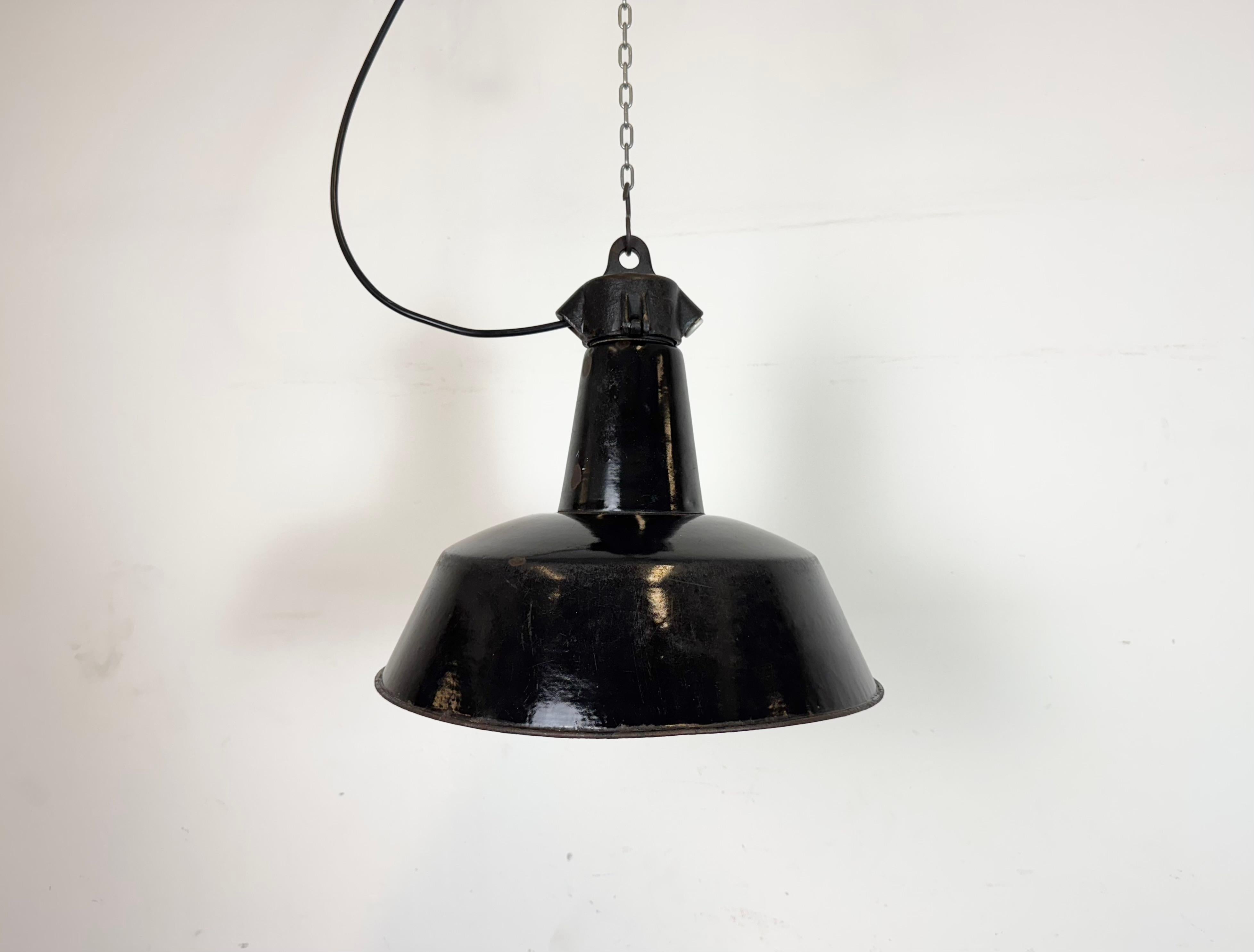 Industrielle Pendelleuchte aus schwarzer Emaille, hergestellt von Elektrosvit in der ehemaligen Tschechoslowakei in den 1950er Jahren. Weiße Emaille im Inneren des Schirms. Platte aus Gusseisen. Die Porzellanfassung ist für normale