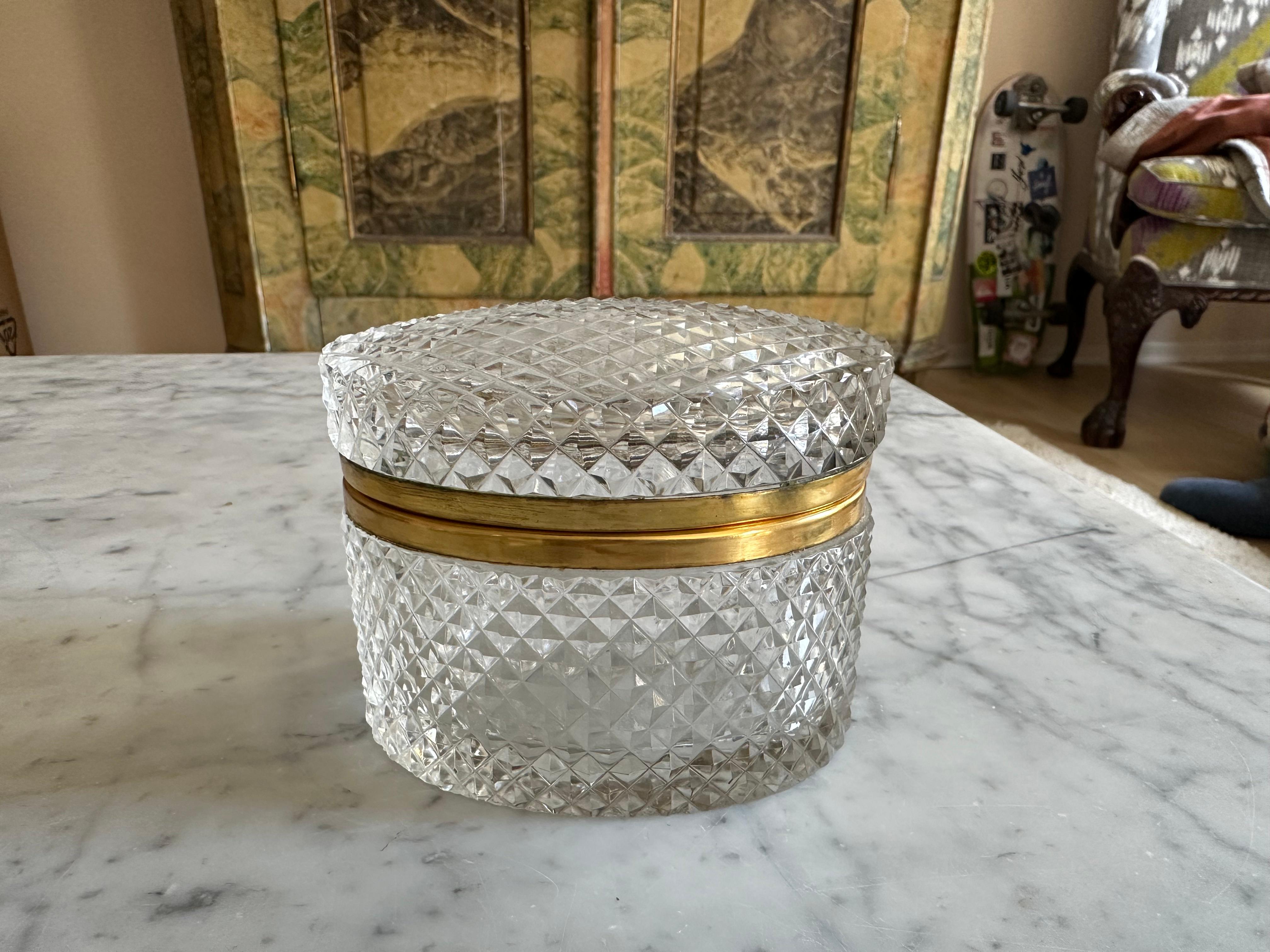 Diese elegante ovale Kristallglasschatulle aus Frankreich stammt aus den 1950er Jahren und besticht durch ihr zeitloses Design und ihre raffinierte Handwerkskunst. Die Dose aus dickem Kristallglas mit klassischem Rautenschliffmuster funkelt
