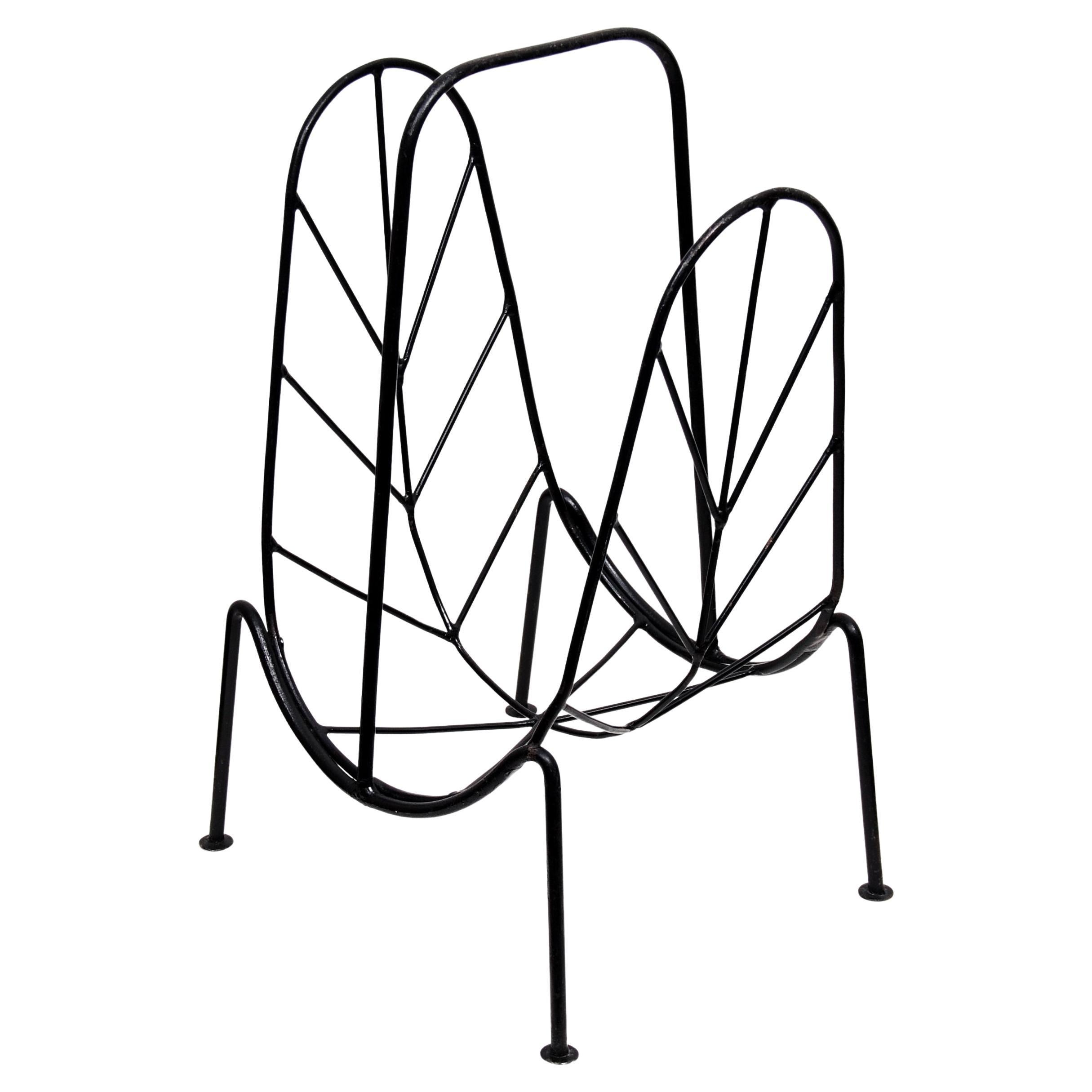 Mid-Century Modern magazine rack in the style of Jacques Adnet. Made in black iron and with beautiful leaf imitated sides. Stamped 'Made In Sweden' on the side of one leg.