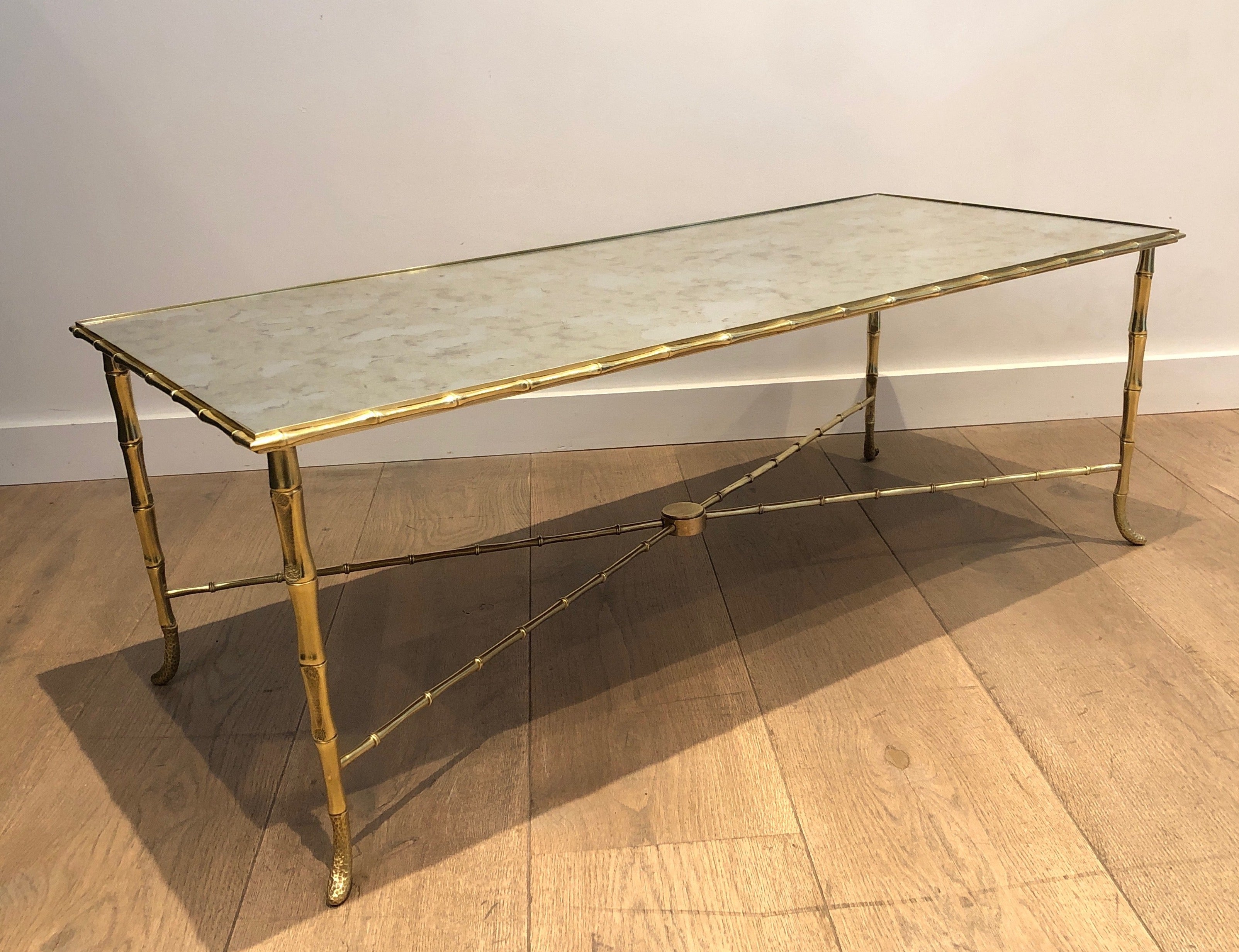 This beautiful faux-bamboo coffee table is made of bronze and brass with a very nice faux-antiques mirror top. This is a French work by Maison Baguès. Circa 1940
