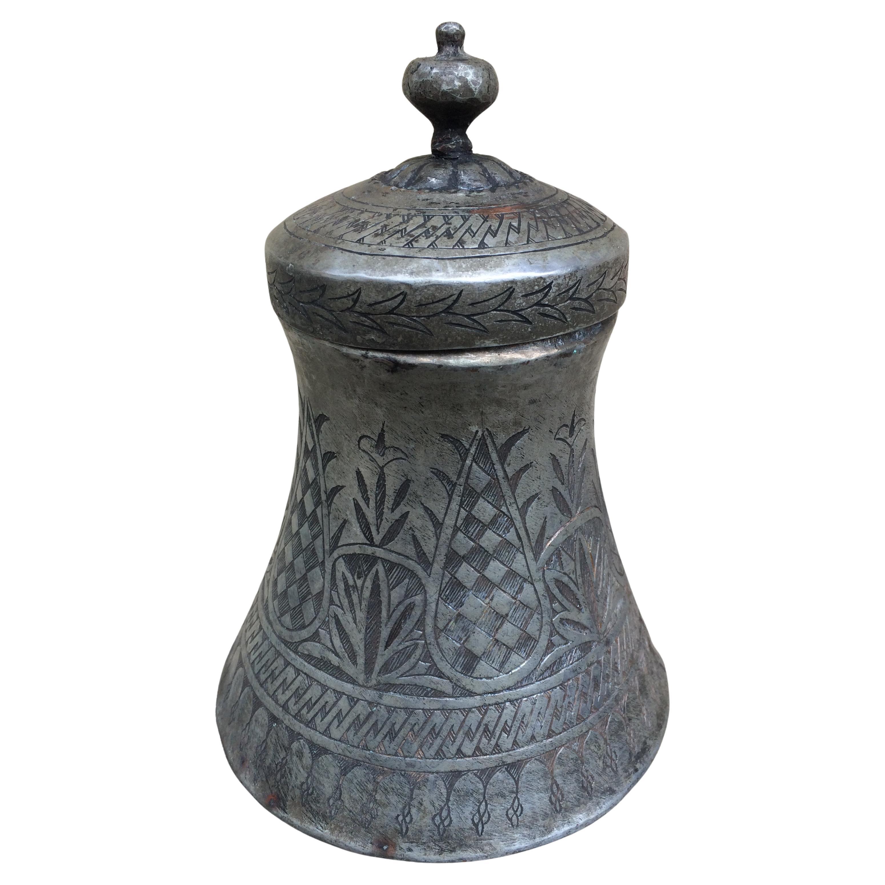 Vaso tradicional con tapa de Oriente Medio o el norte de África, probablemente utilizado con fines ceremoniales o domésticos. Es probable que se trate de un recipiente ceremonial de cobre estañado o peltre del siglo XIX o principios del XX,