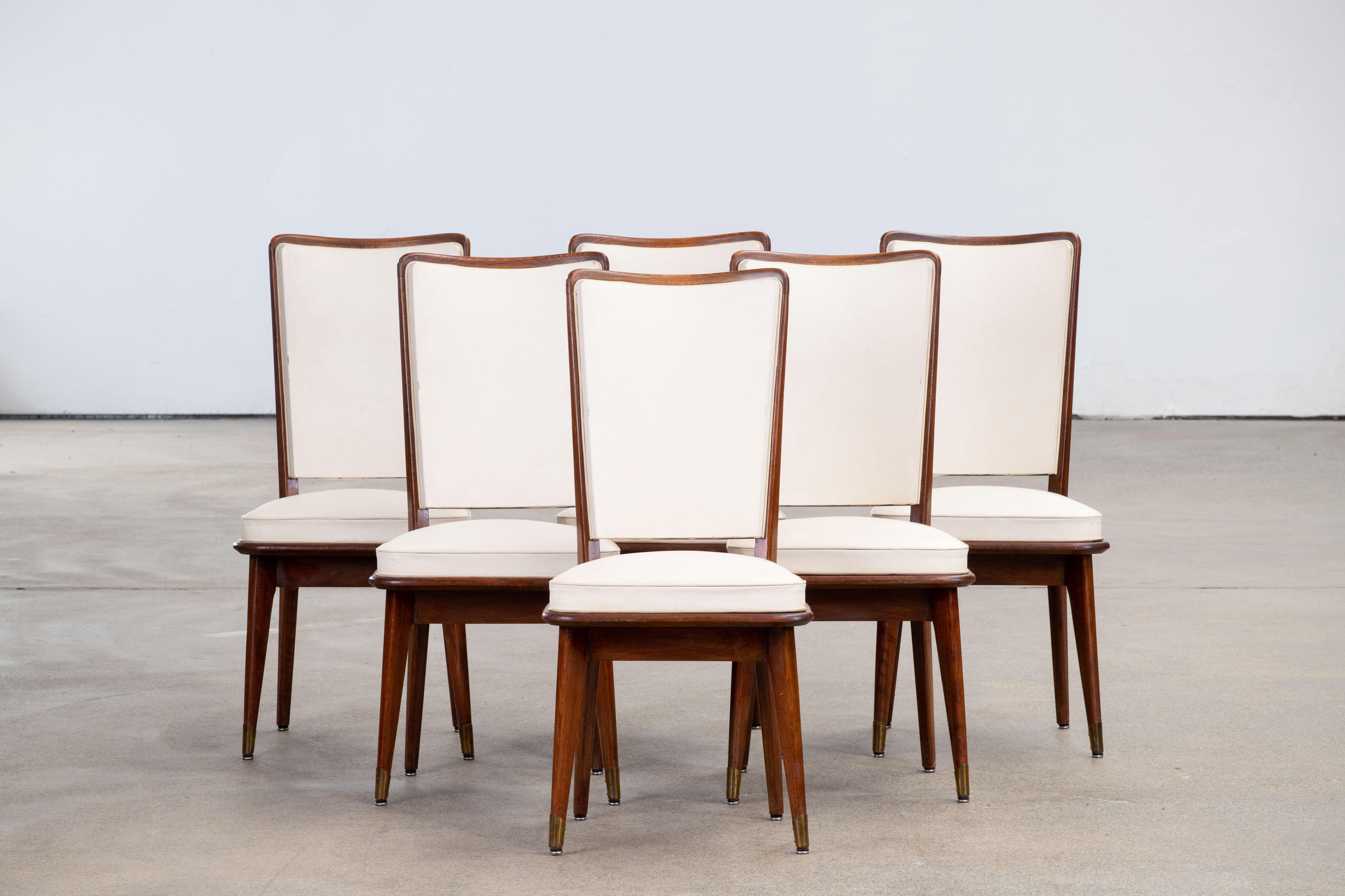 Una composizione di tranquilla sicurezza, questo set di sei sedie da pranzo francesi con schienale alto incarna un linguaggio di proporzioni misurate e discreta raffinatezza. Con un'intelaiatura in rovere massiccio dalla finitura profonda e