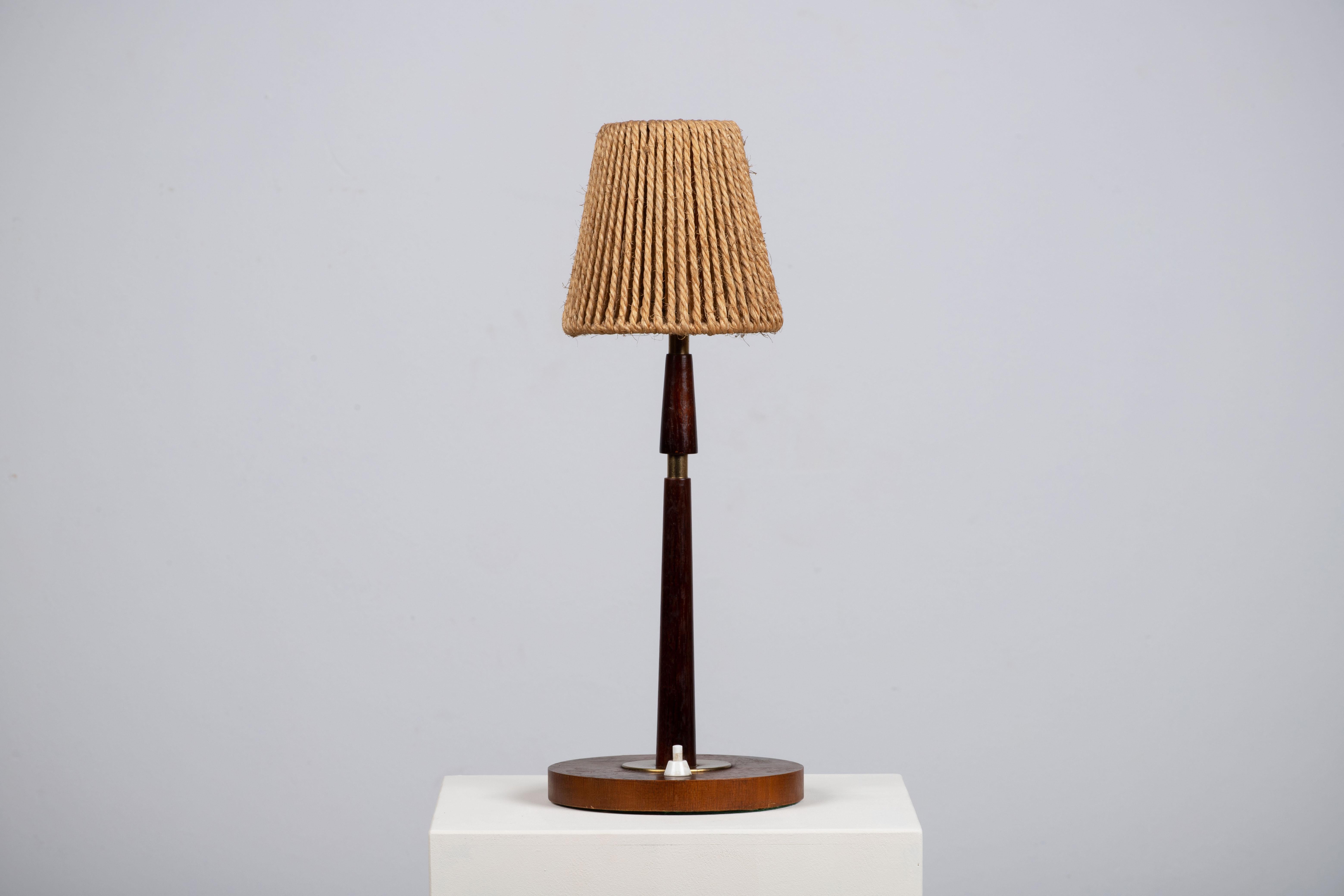 A composition of quiet poise, this Danish table lamp from 1960 reveals a language of sculptural restraint and elemental warmth. Executed in solid teak, the turned shaft rises with an unbroken clarity—its form neither ornamented nor austere, but